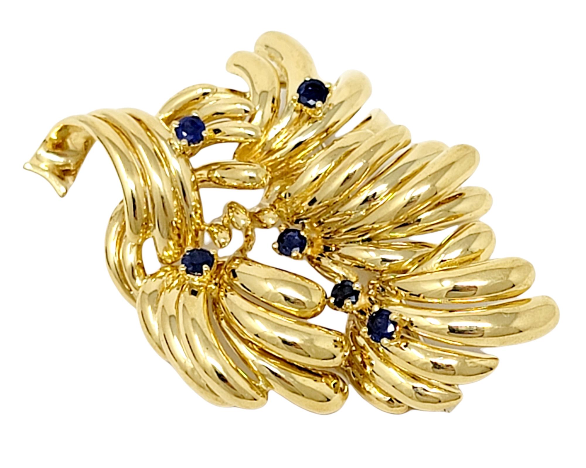 Broche dorado con diseño multihoja de bella textura, acentuado con zafiros naturales de color azul intenso. 

Tipo Broche
Metal: Oro amarillo de 18 quilates 
Zafiros naturales: 0,90 ctw (azul natural con indicios de tratamiento térmico)
Corte