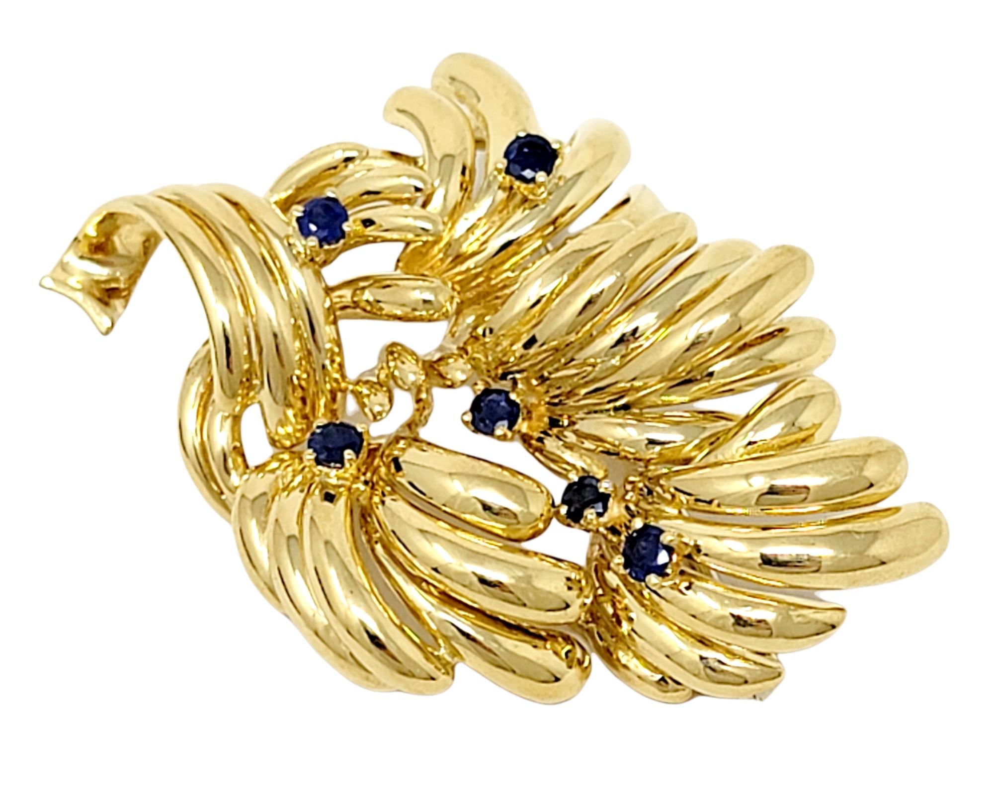 Beautifully textured golden multi-leaf design brooch accented by deep blue natural sapphires. 

Type: Brooch
Metal: 18K Yellow Gold 
Natural Sapphires: .90 ctw (natural blue with evidence of heat treatment)
Sapphire cut: Round
Brooch Width: