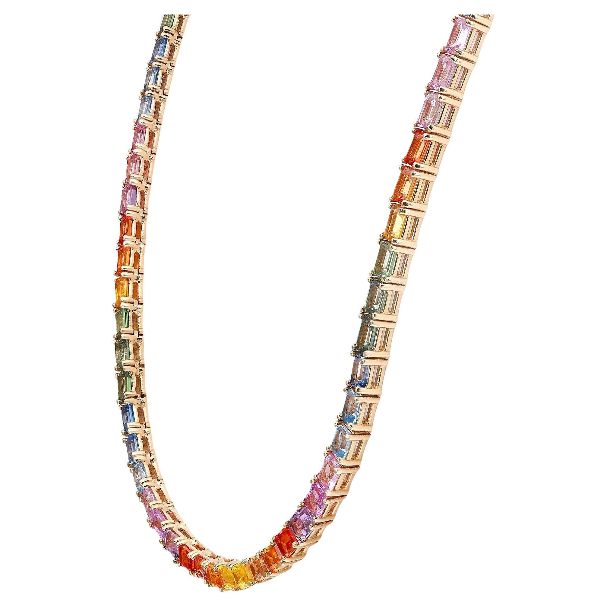 A classic yet vibrant rainbow tennis necklace blazing with the brilliance of 101 emerald cut natural multi-colored sapphires with a total weight of 26.12 carats. Crafted in 14k yellow gold in four prong setting. Necklace length: 17.5 inches. Width: