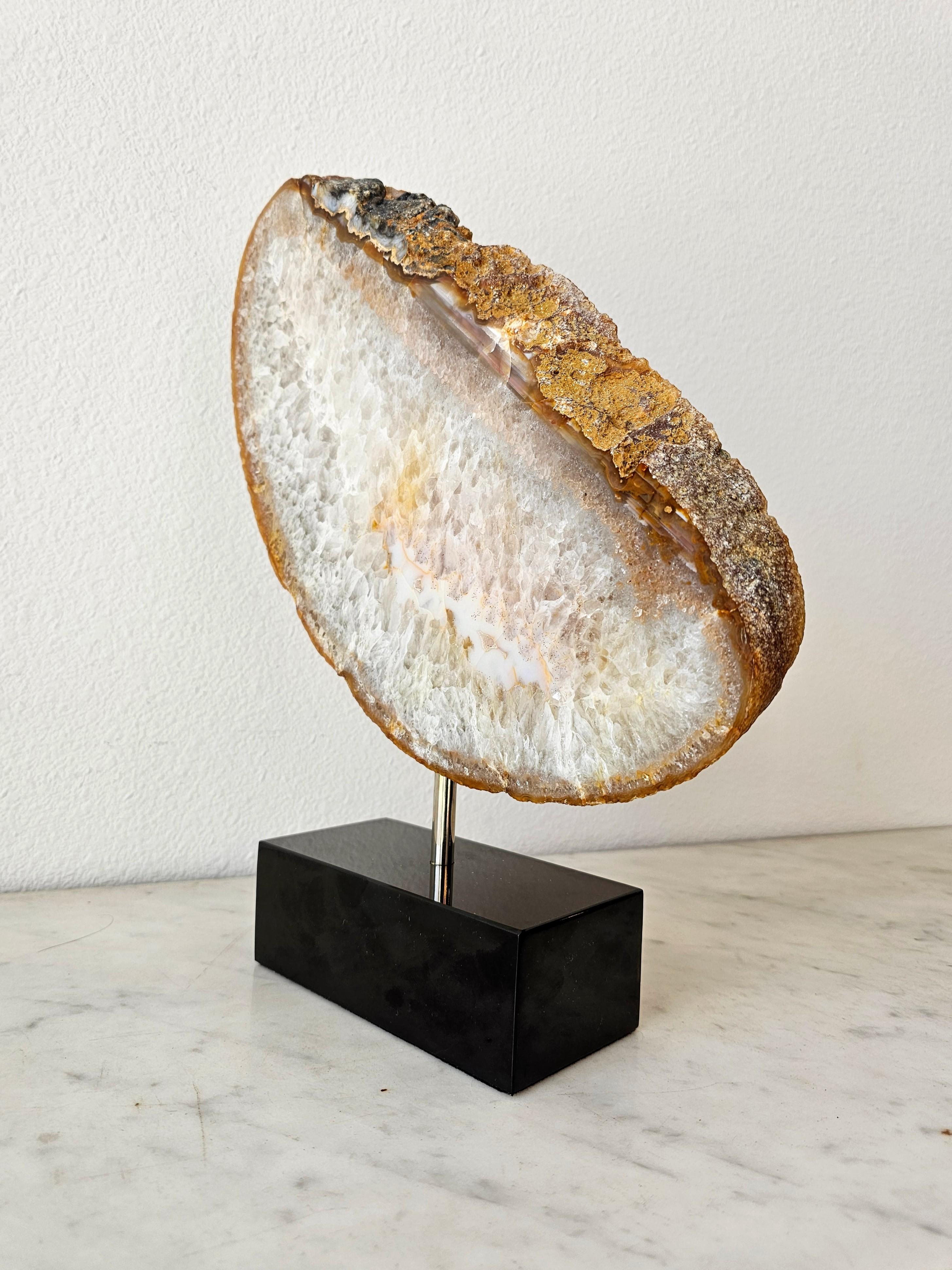 A visually striking natural polished agate gemstone slice, sculptural organic free-form, stunning example with rich patterns of color, transparency and distinctive inclusions, mounted on a contemporary rectangular black marble base stand.

For