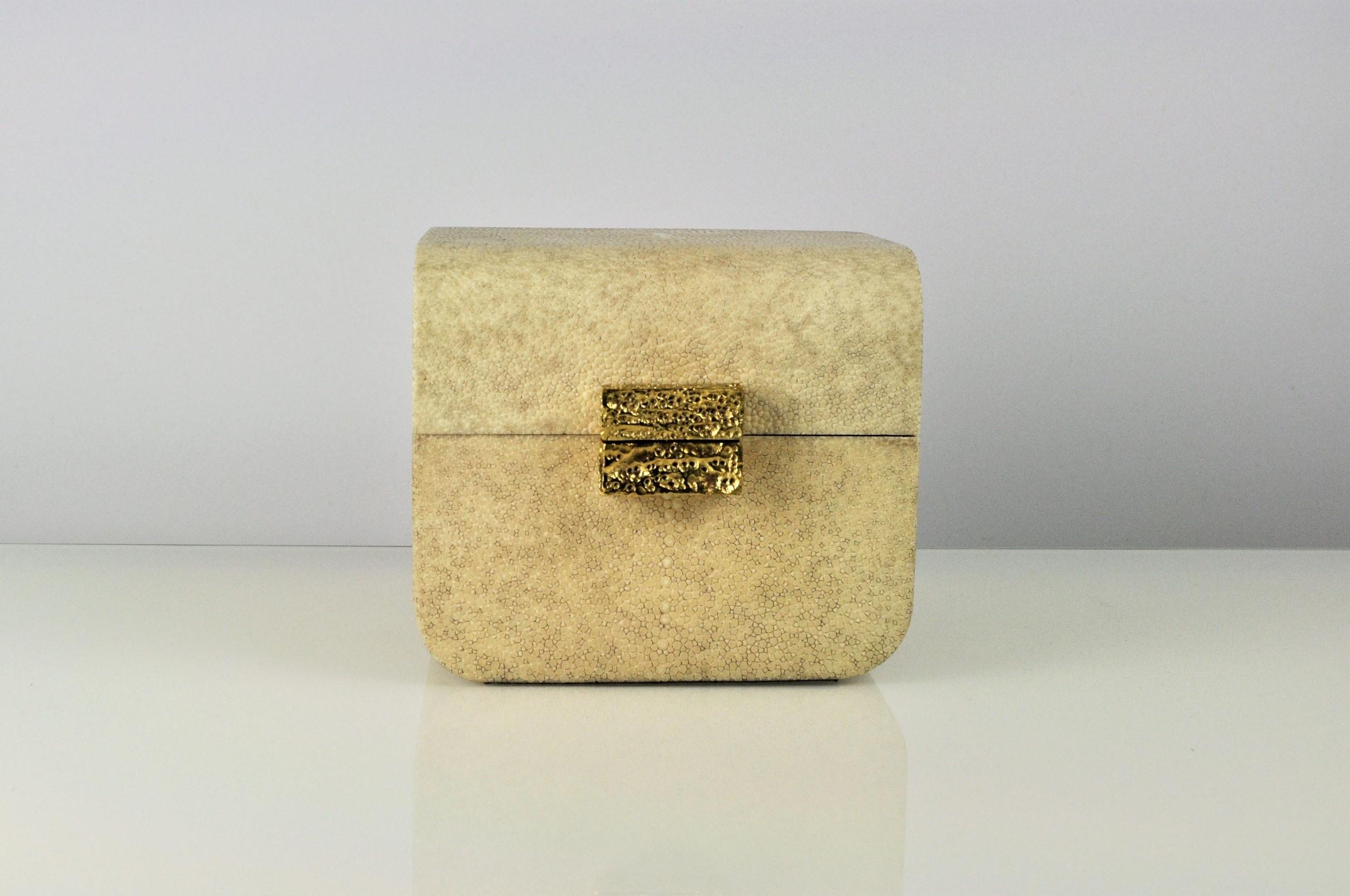 This elegant box is made of shagreen and brass.
The handle has been casted in brass with the lost wax technique. The hammered finishing gives an artistic aspect. 

The box is hinged and the interior is cover with a brown micro suede.

The color