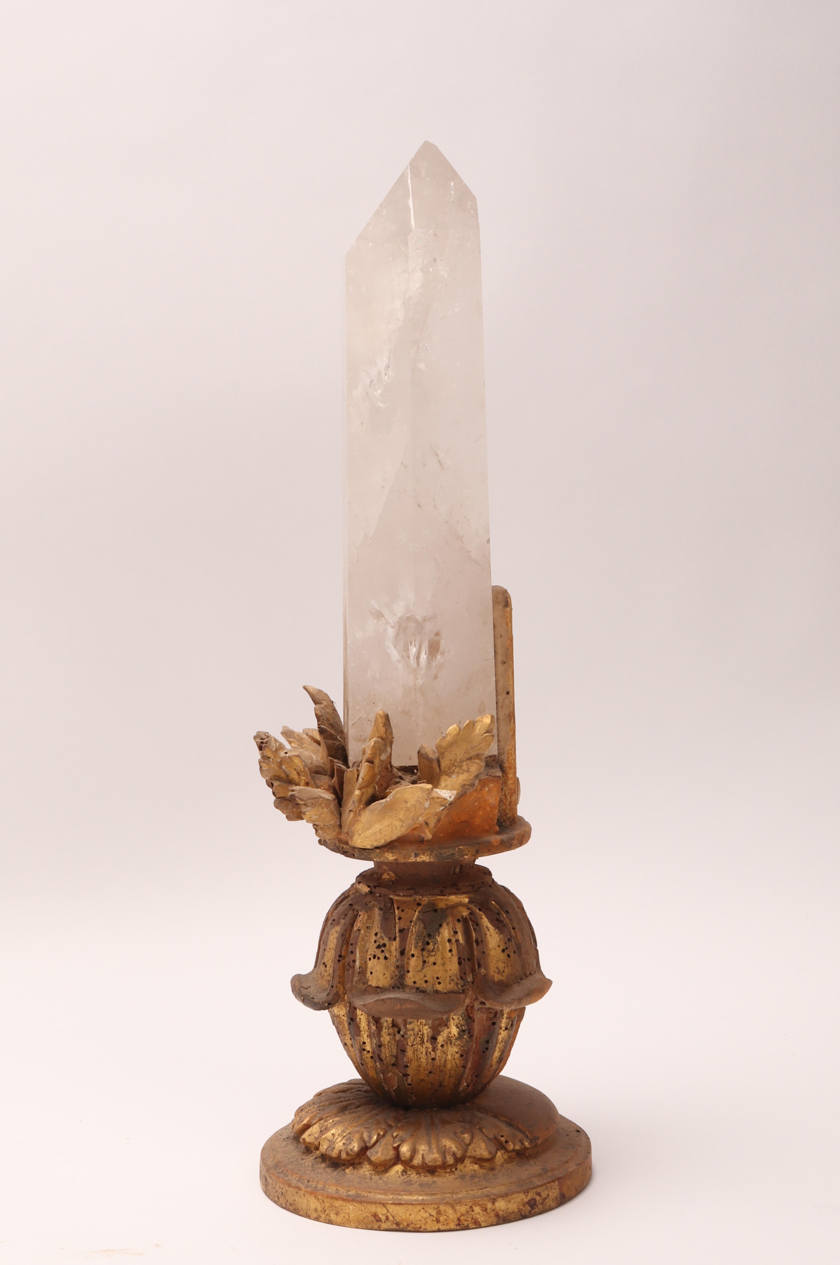 A Naturalia mineral specimen. A big rock crystal mounted over a carved wooden base gold gilt with carved leaves. Italy 1870 ca.