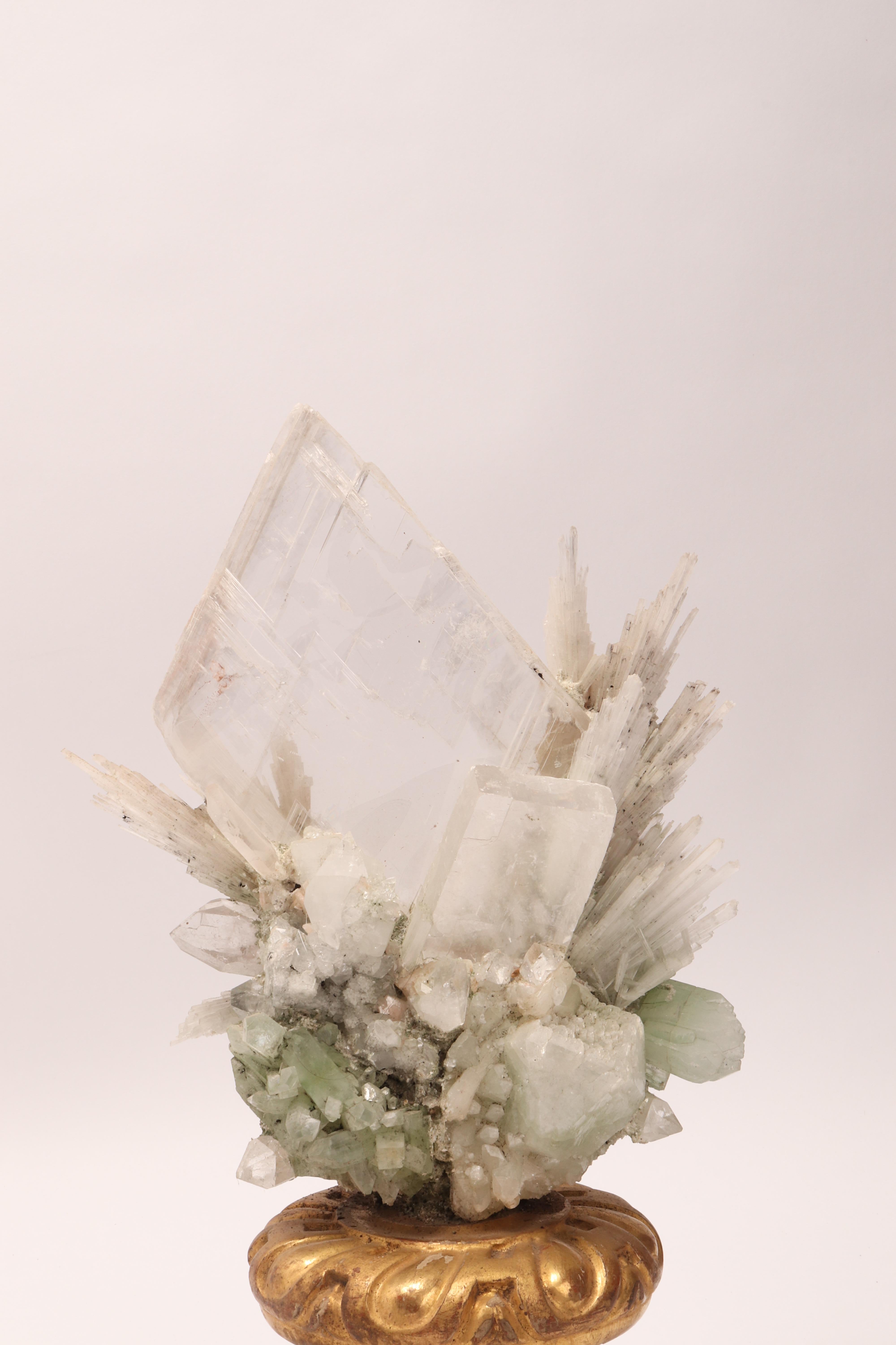 A Naturalia mineral specimen. A Druze of apophyllite, quartz, colacyte, and calcite flowers crystals, mounted over a guild-plated wooden base on a vase shape, Italy, circa 1880.