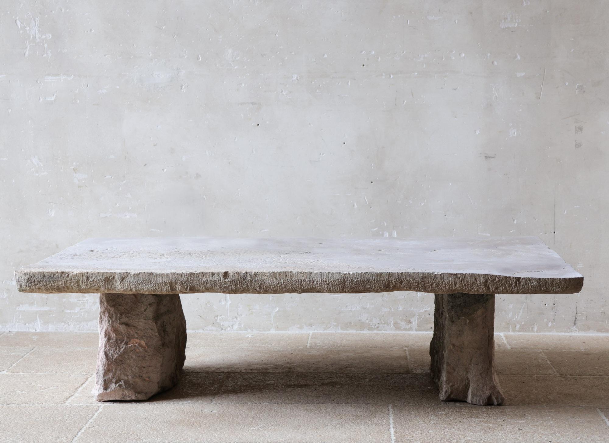 This imposing coffee table is a rare and authentic piece with exceptional character. The tabletop is crafted from a 6 cm thick threshold stone dating back to the 17th century, sourced from the heart of Burgundy. All four original, hand-carved edges
