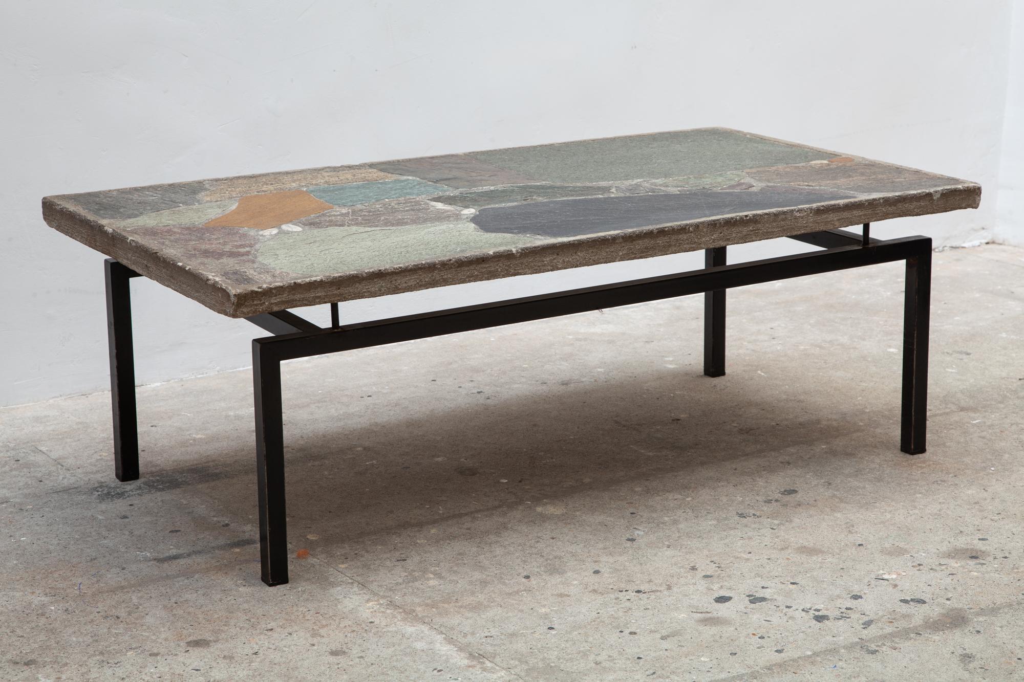 Vintage midcentury coffee table on a black metal base. A beautiful mosaic of slate and other stones in shades of grey, green and brown designed by the Dutch sculptor Paul Kingma,1960s.

Paul Kingman, born in 1931, was a sculptor and mosaic artist.