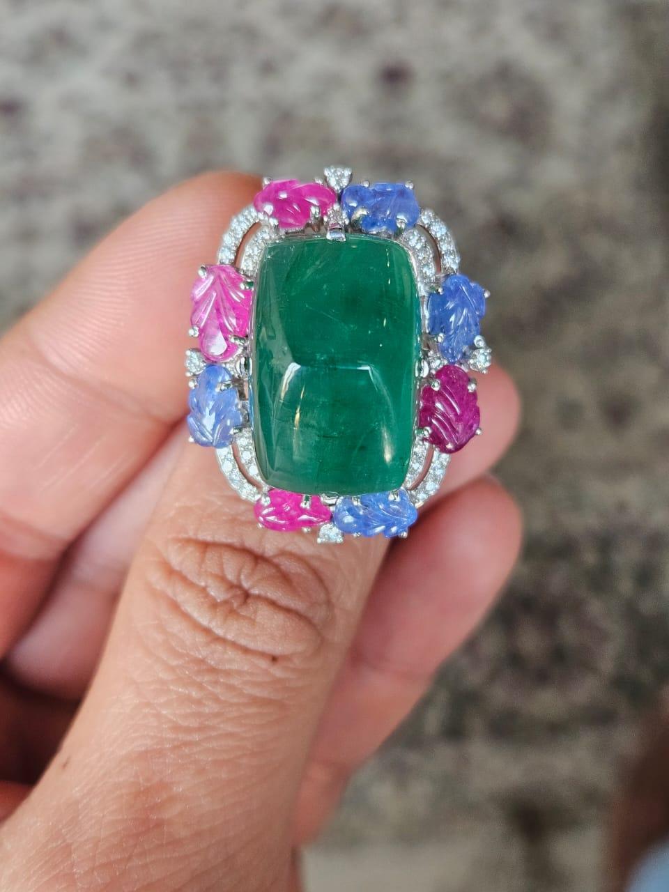 A very gorgeous and beautiful, modern style, Emerald, Blue Sapphires & Rubies Cocktail Ring set in 18K White Gold & natural Diamonds. The weight of the Emerald Sugarloaf is 25.58 carats. The Emerald is completely natural, without any treatment and