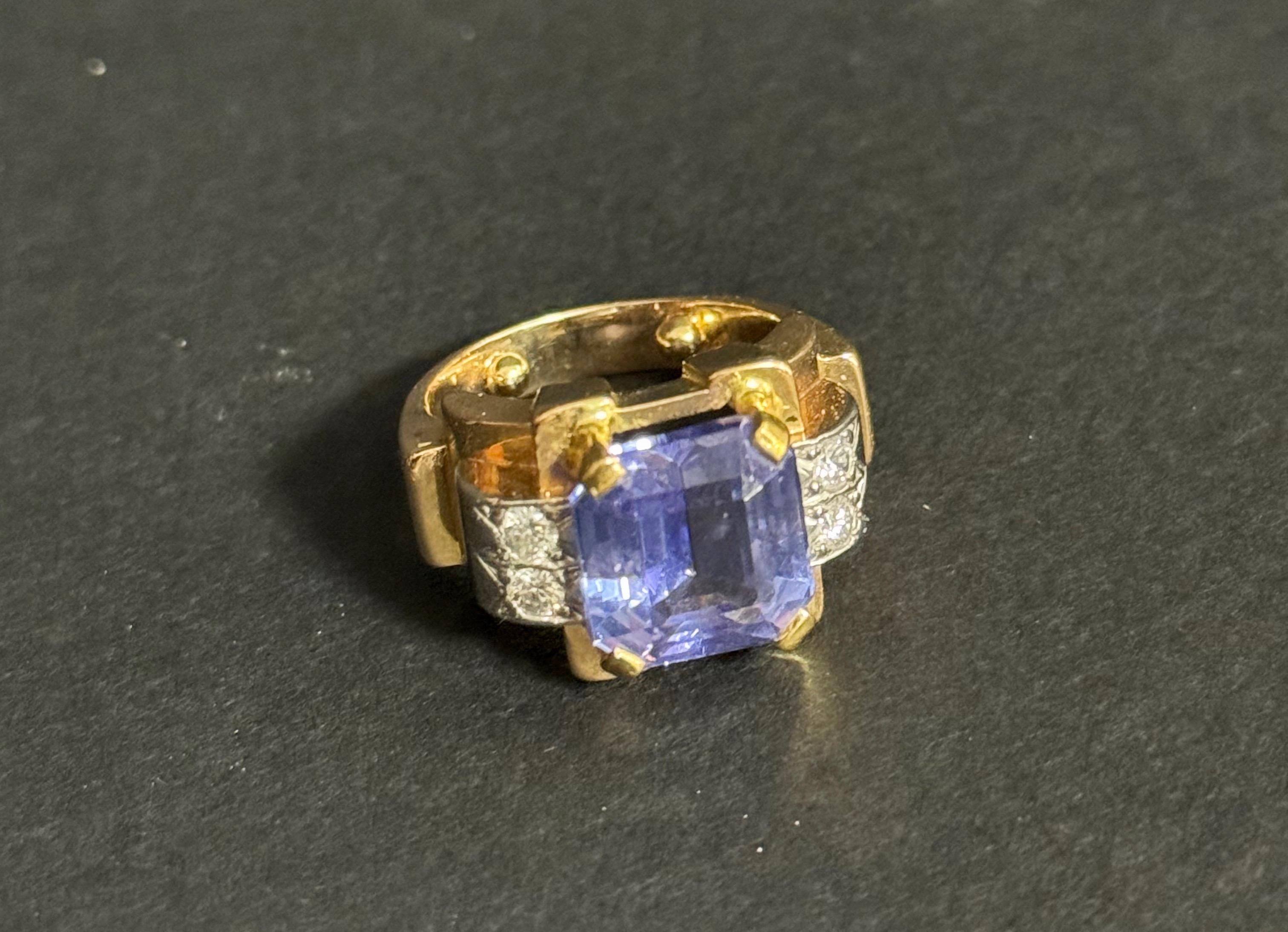 Wunderschöner Panzerring mit Tansanit und Diamanten aus den 1930-50er Jahren. Der Tansanit ist natürlich und hat einen achteckigen Schliff. Die Farbe ist purpurblau. Er misst 10,52 x 10,15 mm und wiegt 6,62 Karat. Es hat ein AIG-Zertifikat.