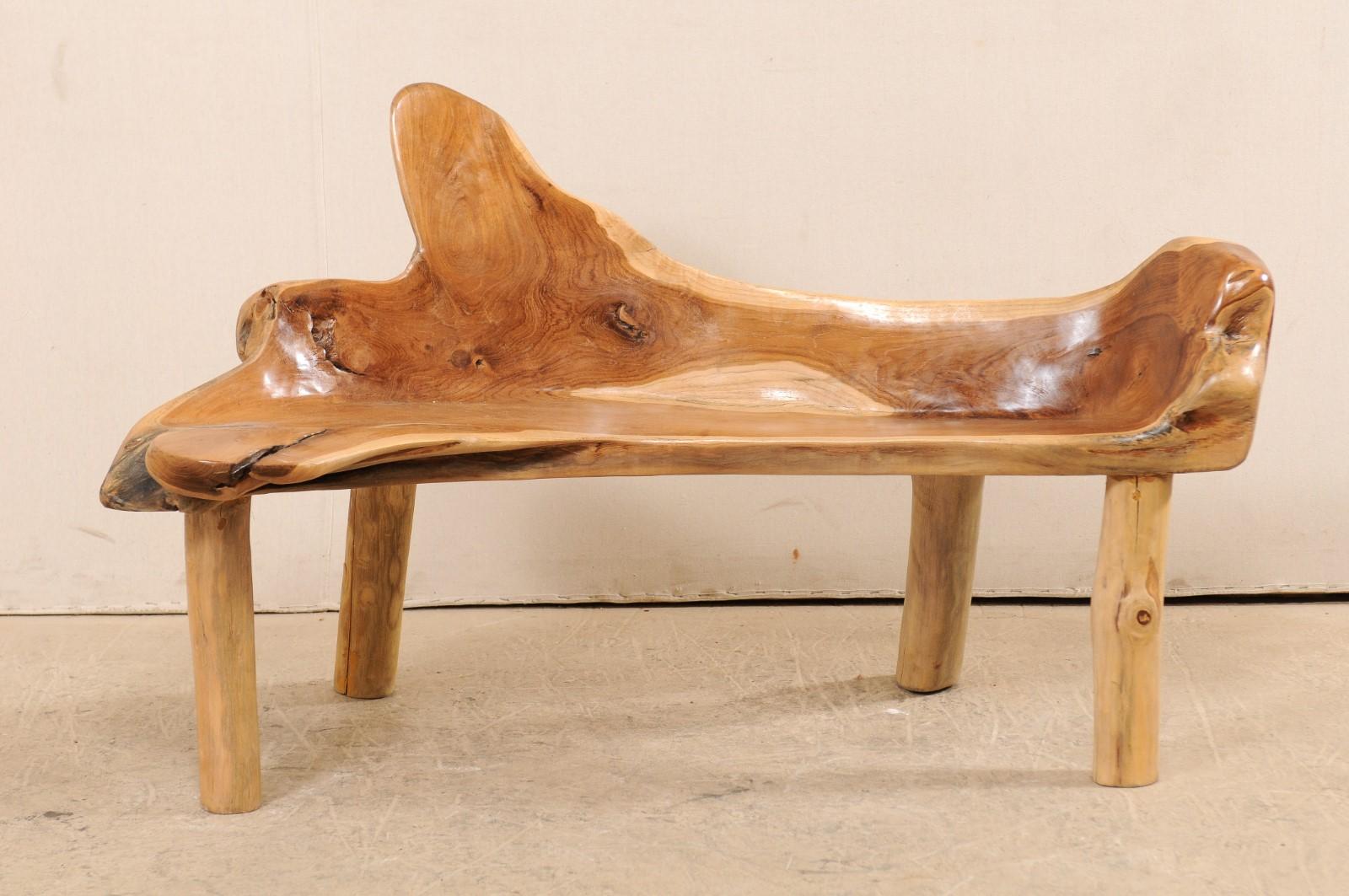 A natural teak wood bench with live edges. This delightful bench, approximately 4.5 feet in length, has been created from the root and limbs of Indonesian teak wood, which has been smoothed and polished. Teak is a tropical hardwood which is