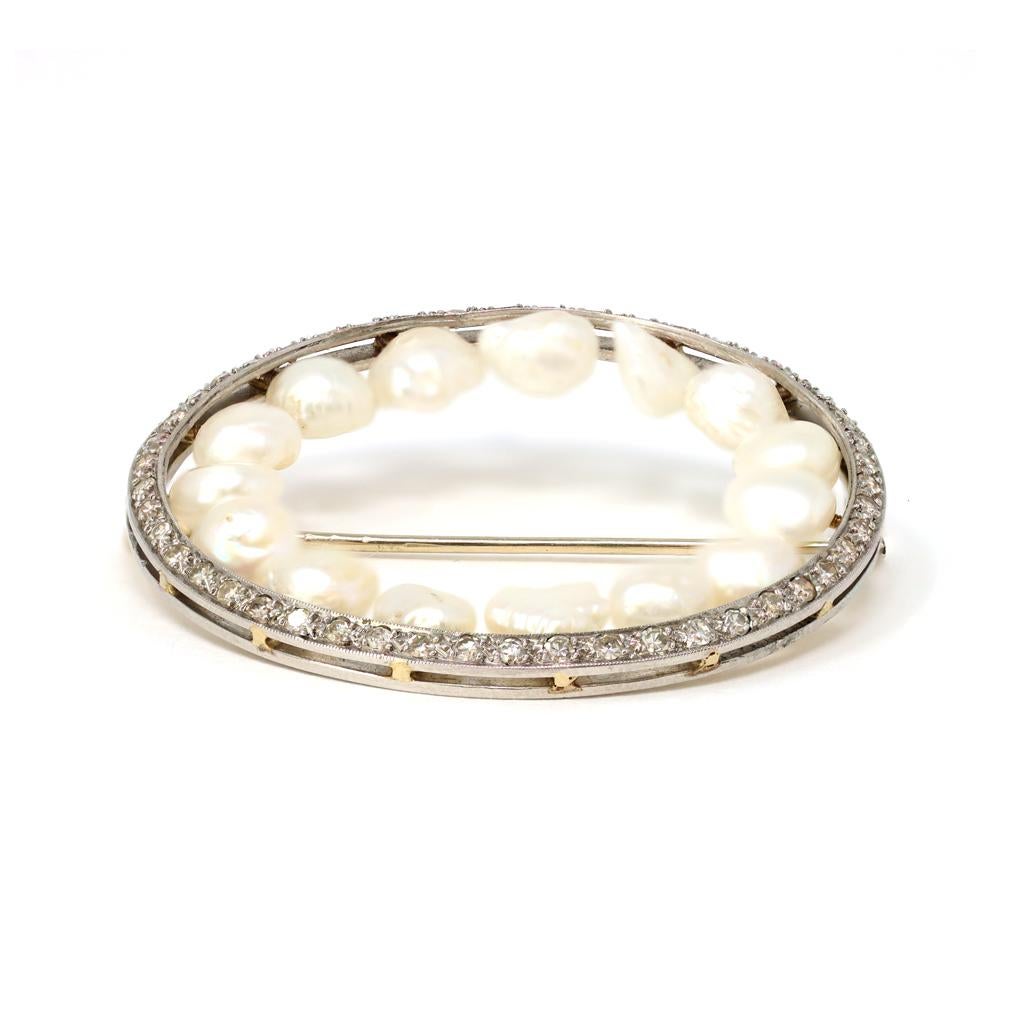 A brooch in the shape of an infinity circle featuring natural freshwater Tennessee River pearls with a line of single cut diamonds set as a ring around the pearls in platinum. The brooch was created in the US circa 1930. The baroque shape pearls