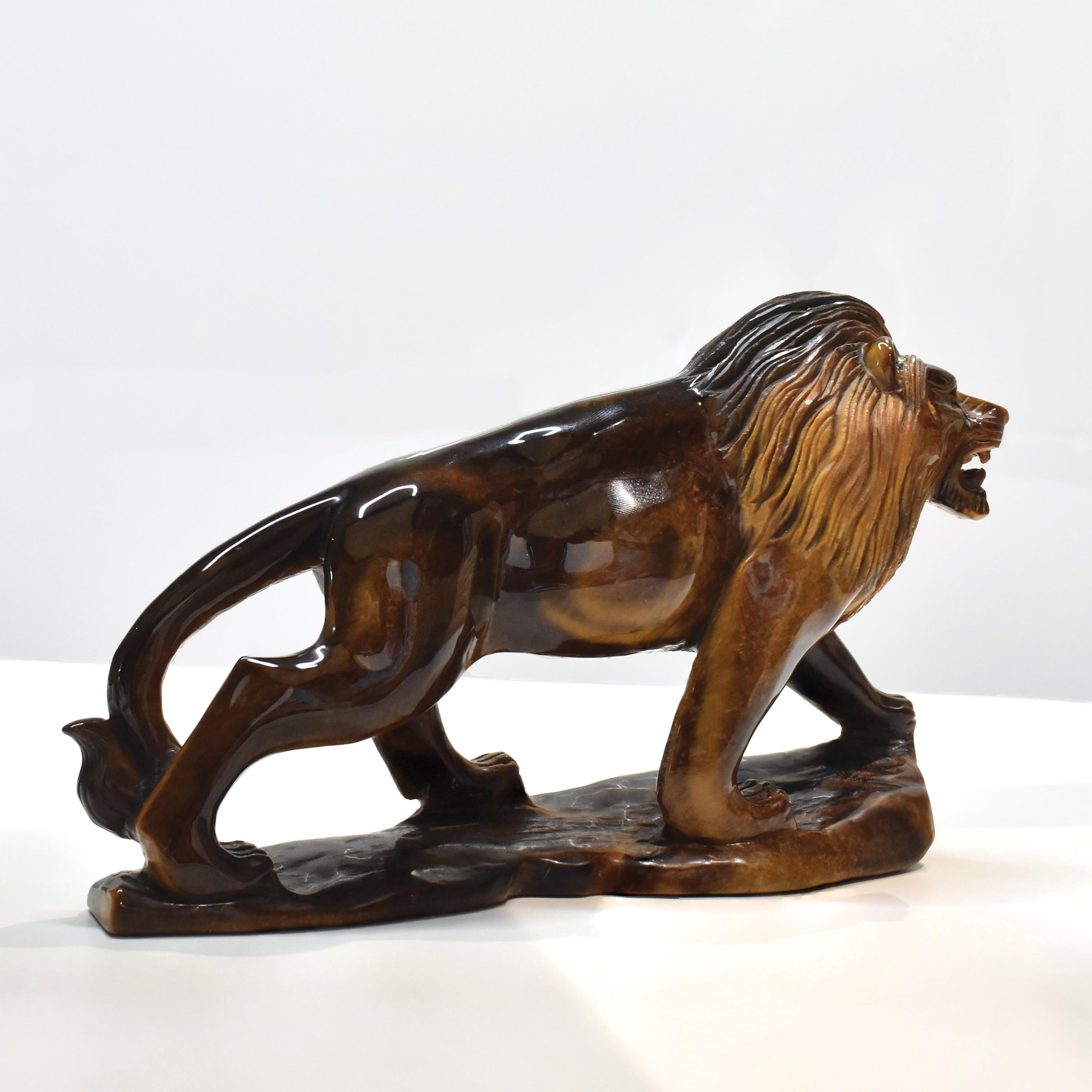 Command attention with this majestic hand-carved lion sculpture, skillfully shaped from a single block of natural Tiger’s Eye—a gemstone revered for its grounding energy, golden sheen, and powerful symbolism. Measuring 22.9 cm in length and 13.8 cm