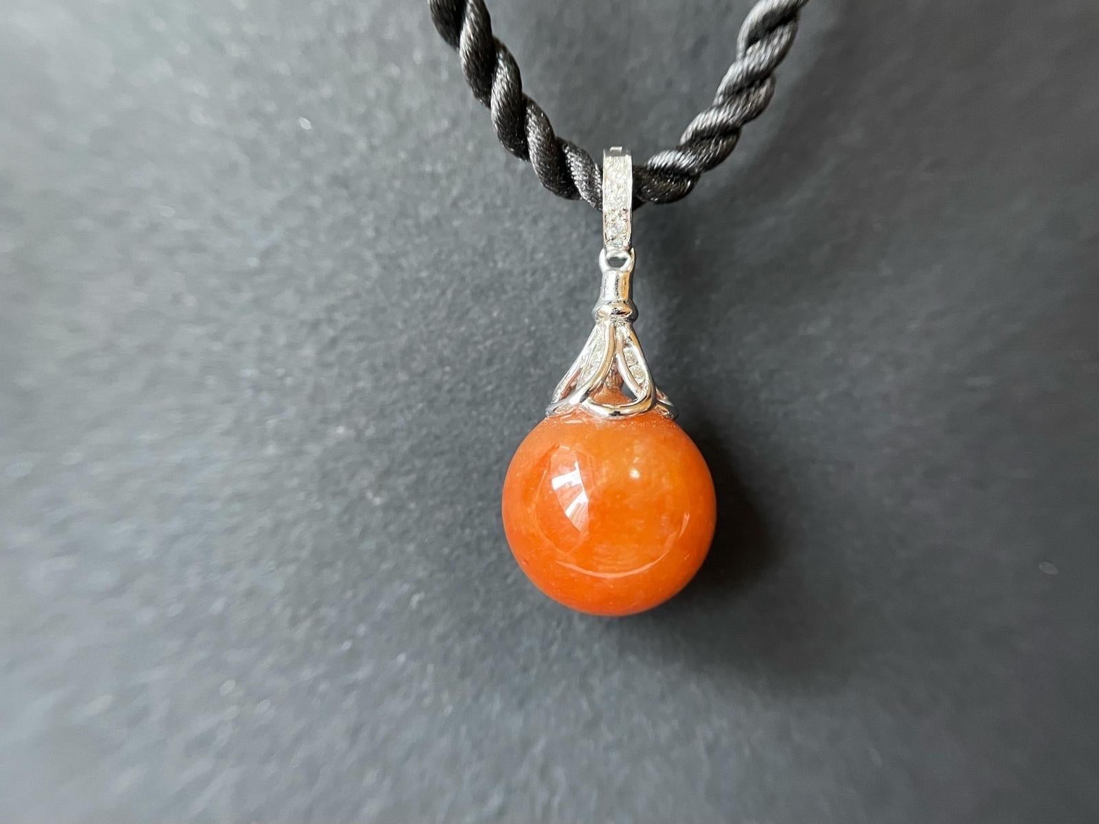 Genießen Sie die Schönheit und Kraft der Jadeit-Jade mit diesem exquisiten Anhänger aus roter Jadeit-Jade. Dieser Anhänger aus natürlichem Jadeit Typ A hat eine atemberaubende rote Farbe, die einfach atemberaubend ist. Die glatte Textur der Kugel