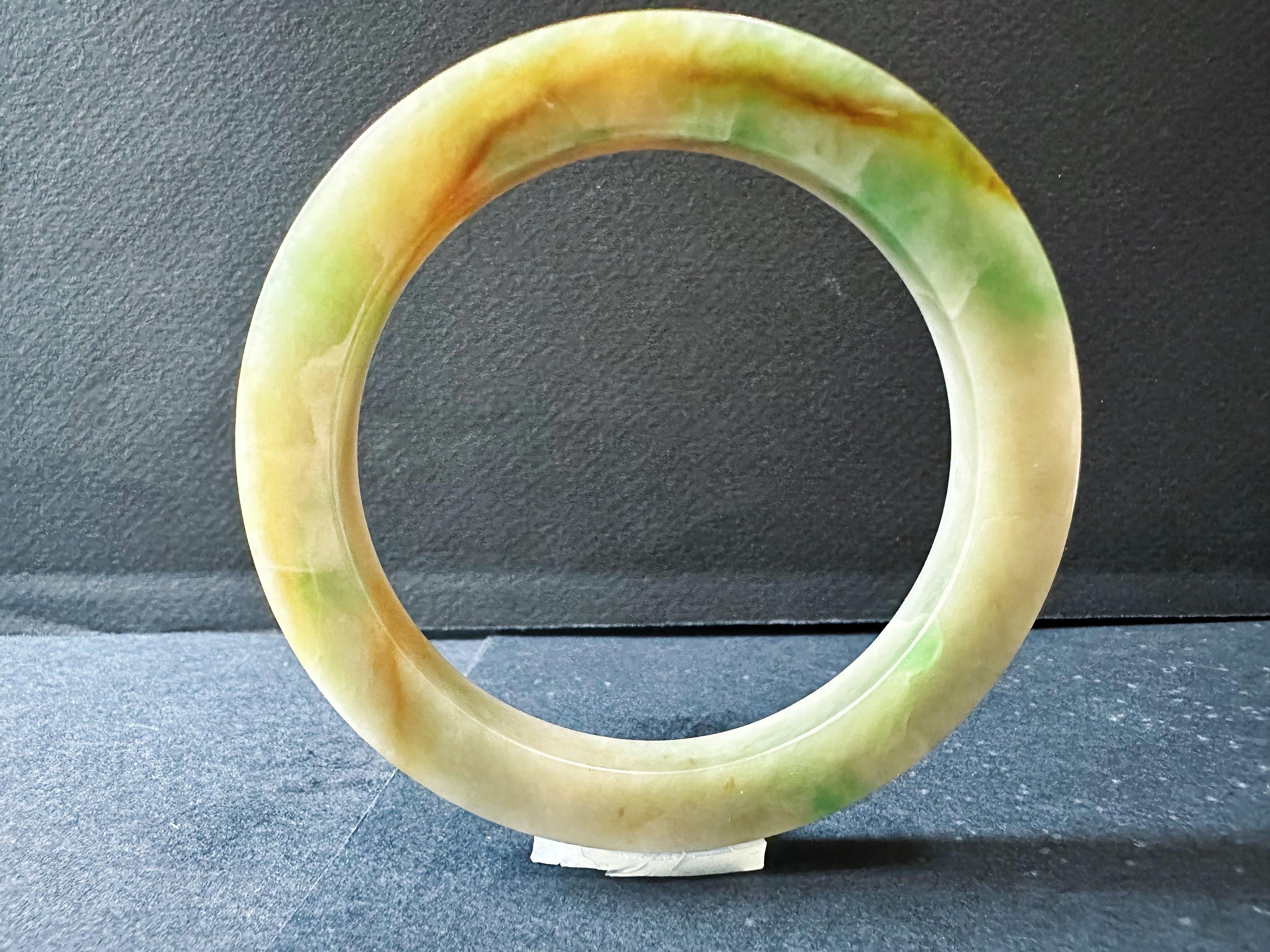 Erleben Sie die exquisite Schönheit dieses 100% natürlichen, unbehandelten und ungefärbten Jadeit-Armreifs aus Myanmar. Dieses atemberaubende Stück zeigt eine einzigartige Kombination aus leuchtenden Farben - Rot, Gelb und Grün -, die von Mutter