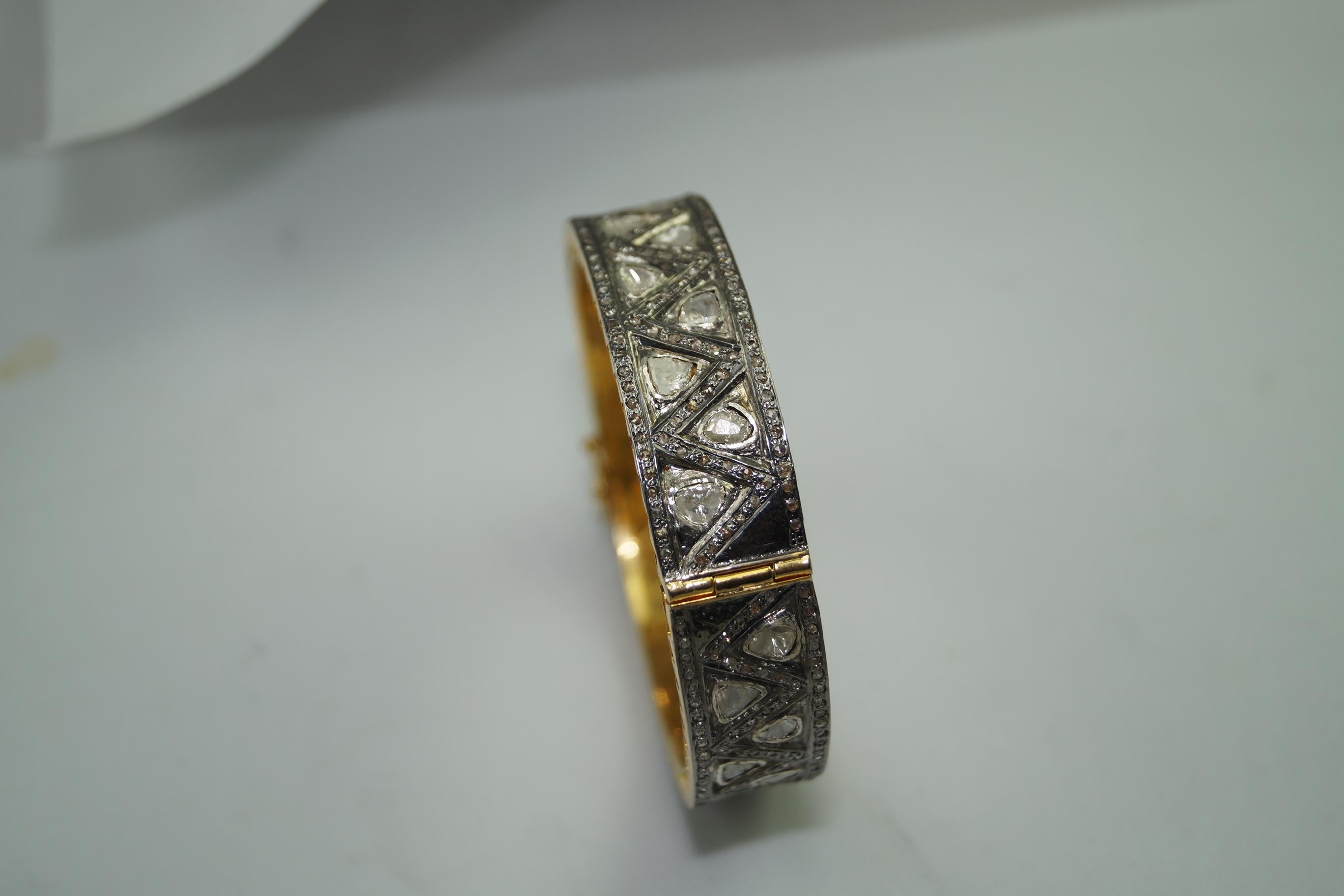 This vintage style diamond silver and yellow gold plating hinged bangle consists of:

Diamond- 7.60cts
Diamond type: Rose cut diamonds and uncut polki diamond
Diamond color:  white and tinted yellow
Diamond origin- Natural
Metal: Silver
Metal