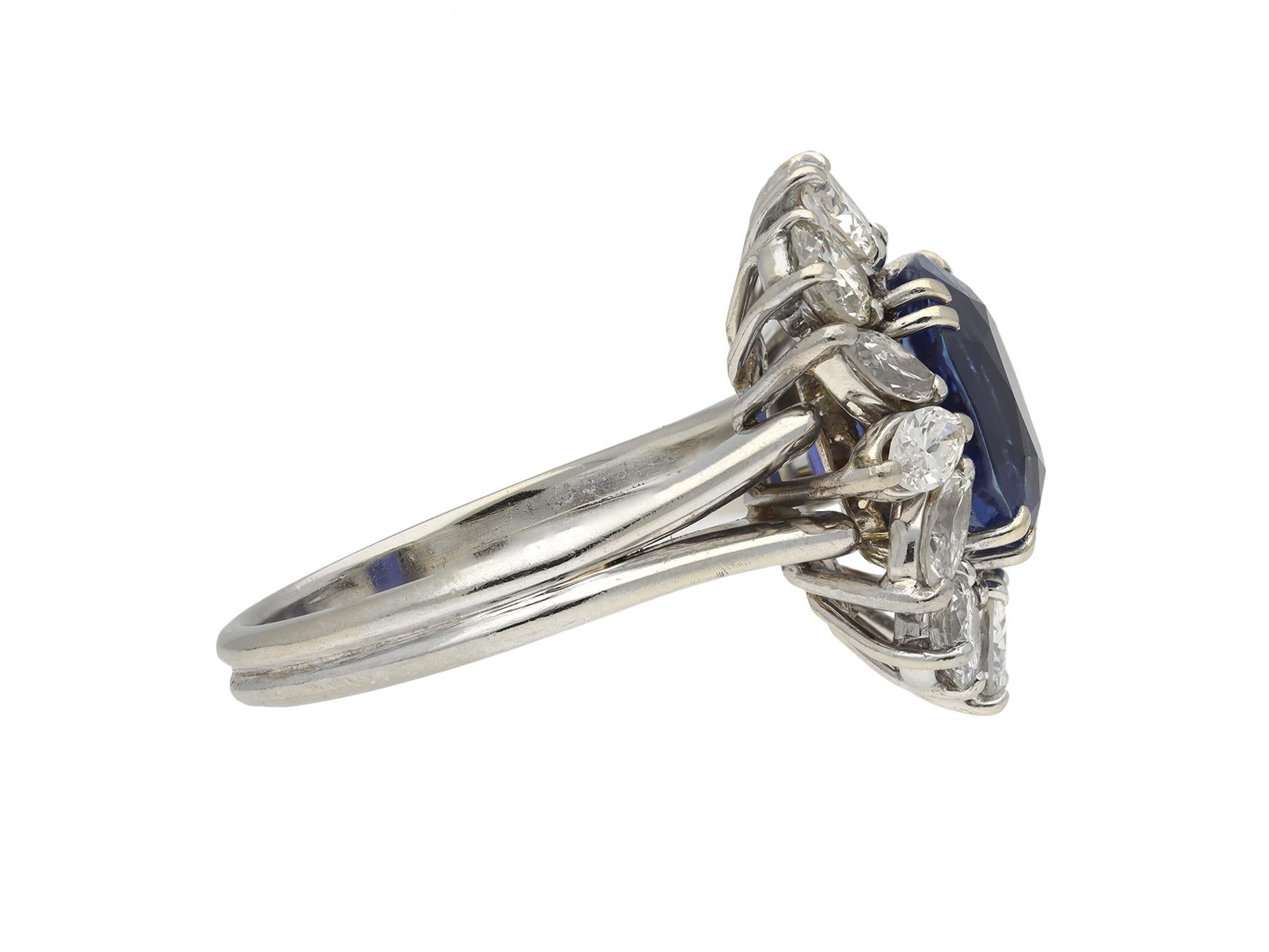 Ceylon sapphire and diamond cluster ring. Centrally set with a cushion shape old cut natural unenhanced Ceylon sapphire in an open back claw setting with an approximate weight of 5.70 carats, further set with six round brilliant cut diamonds in open