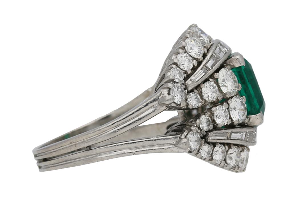 Colombian emerald and diamond cluster ring. Set with a rectangular emerald-cut Colombian emerald with no colour enhancement in an open back corner claw setting with an approximate weight of 2.00 carats, flanked to top and bottom by two curving