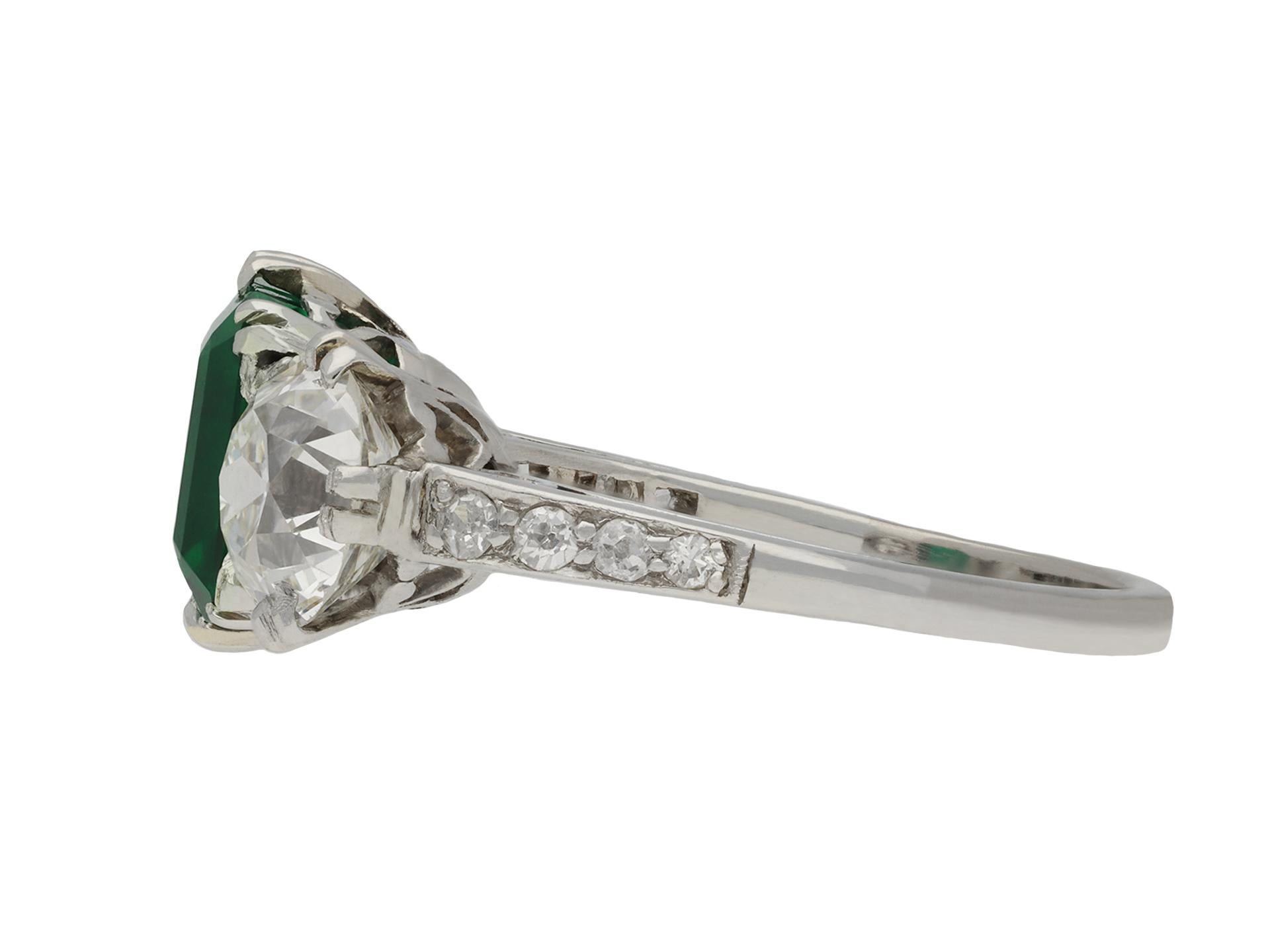 Colombian emerald and diamond three stone ring. Set with a rectangular emerald-cut natural Colombian emerald with no colour enhancement and no indication of clarity modification, in an open back claw setting with an approximate weight of 1.37
