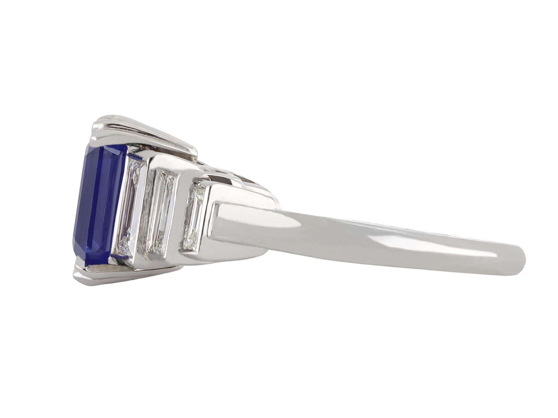 Kashmir sapphire and diamond ring. Centrally set with a rectangular emerald-cut natural unenhanced Kashmir sapphire in an open back claw setting with an approximate weight of 2.12 carats, further set with six tapered rectangular baguette cut