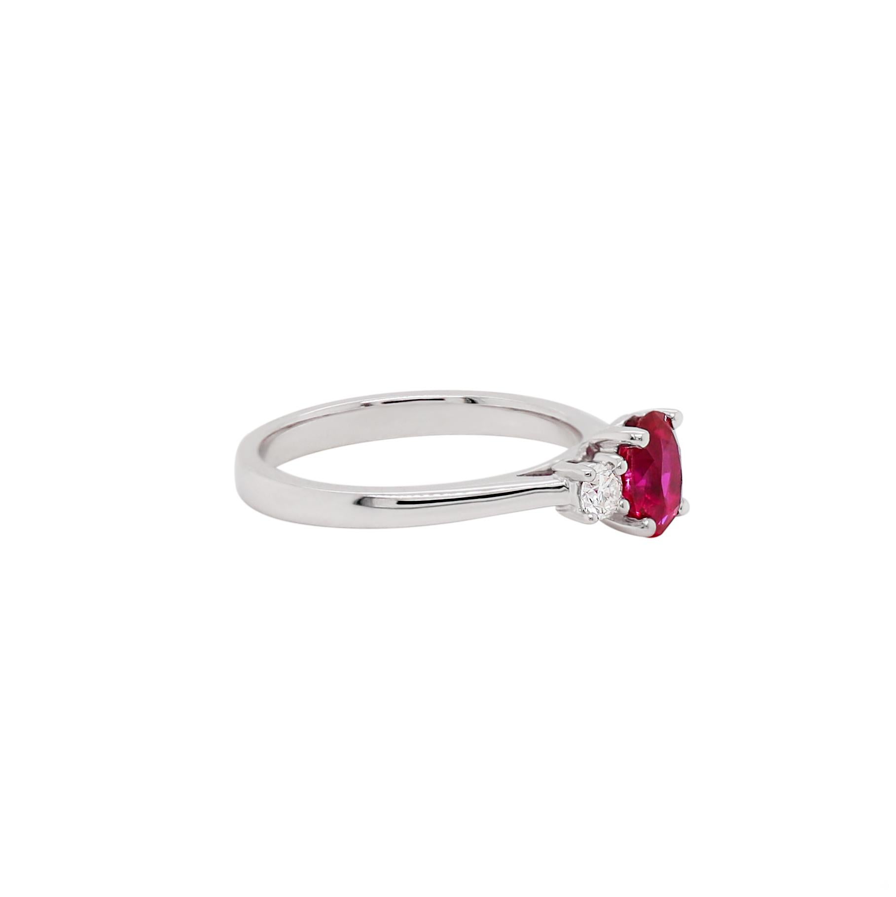 This beautiful three-stone ring features a natural unheated oval shape ruby weighing 1.05 carat in a four claw, open back setting. This lovely stone is accompanied by two round brilliant cut diamonds on either side with a combined weight of 0.22ct