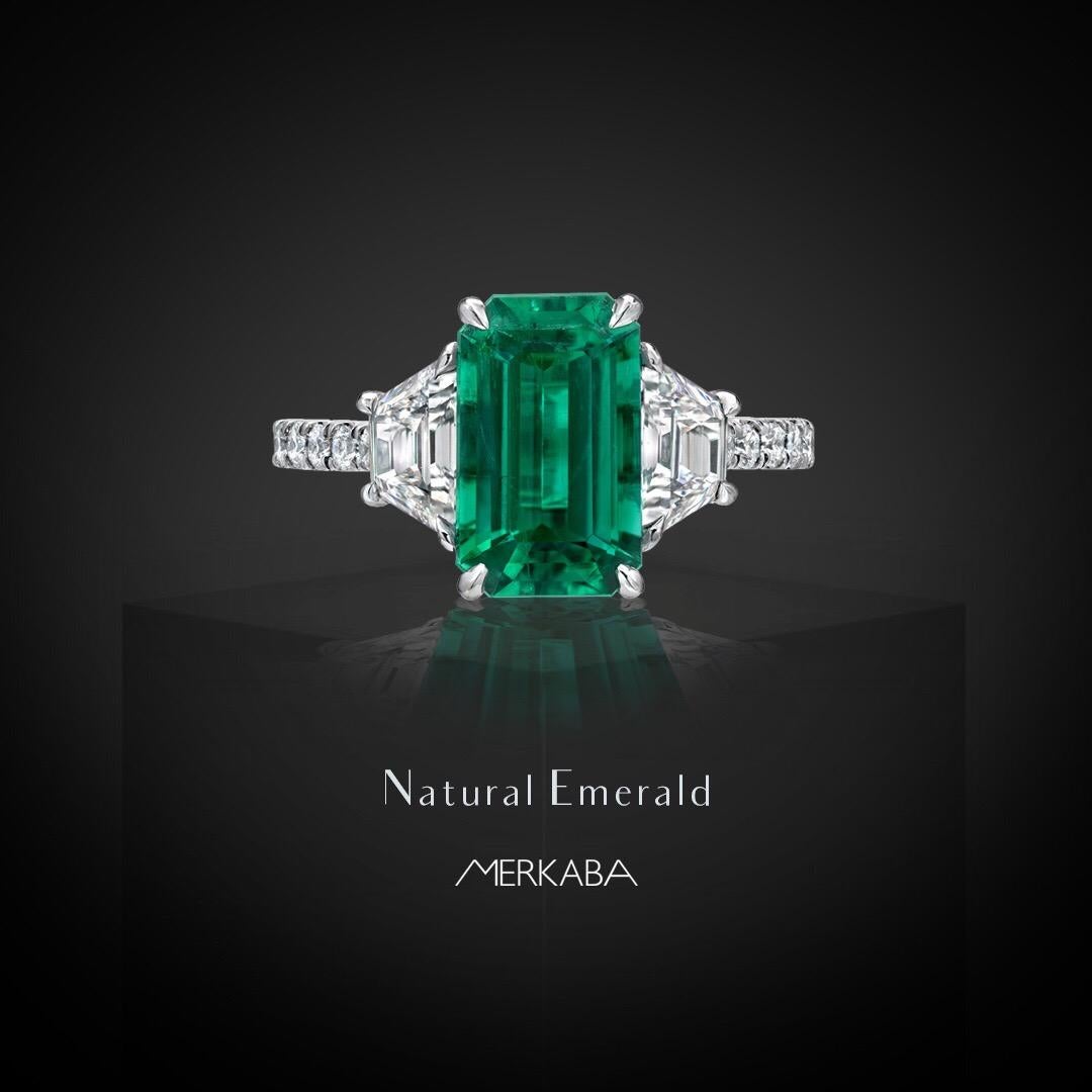 Natural Colombian Emerald ring featuring a rare and esteemed, untreated, no oil Emerald, emerald cut, weighing a total of 2.17 carats, flanked by a pair of E color and VS2 clarity trapezoid diamonds weighing a total of 0.82 carats, and adorned by