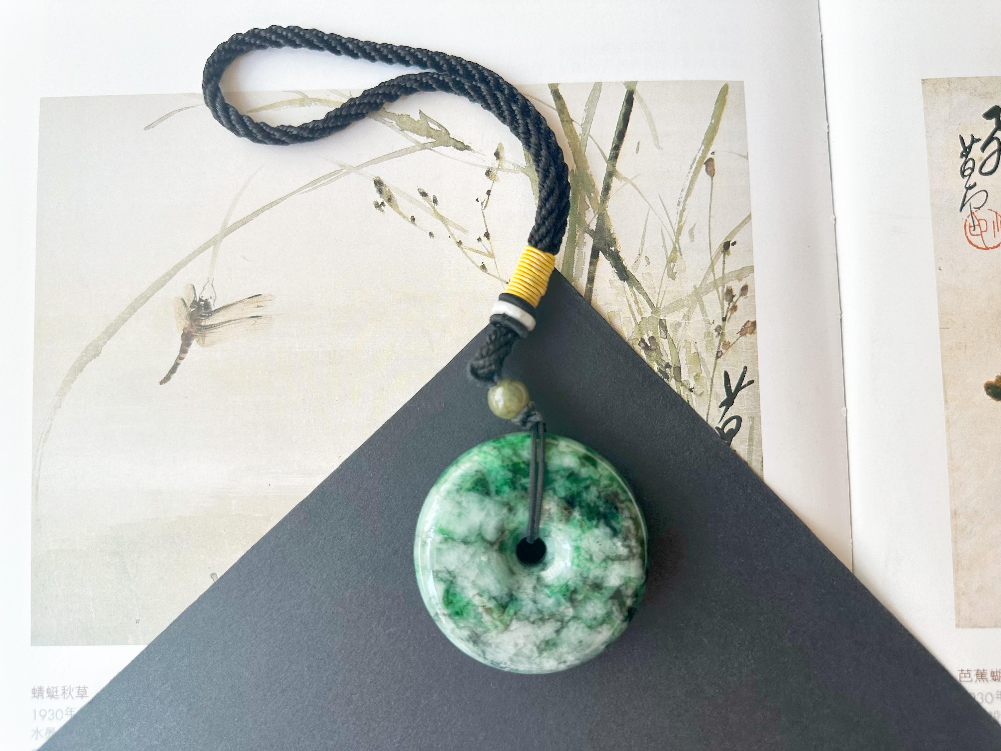 Rehaussez votre style avec notre superbe pendentif/pierre de jade vert en forme de beignet, fabriqué à partir de jadéite du Myanmar de type A de première qualité. Cette pièce unique présente un magnifique dégradé de verts, mettant en valeur la