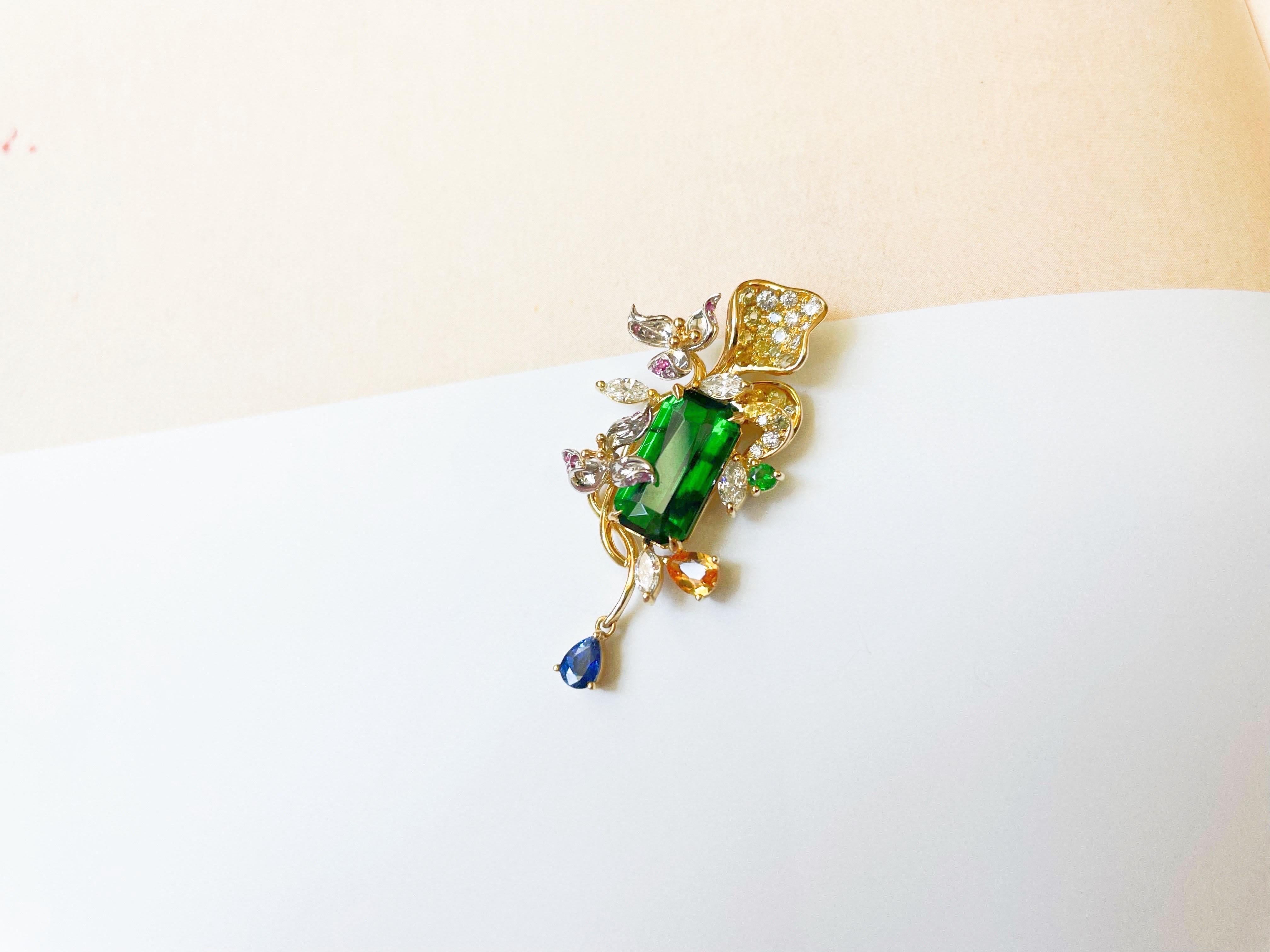Este colgante de tsavorita verde bosque decorado con diamantes naturales, zafiros de colores y rubíes es una pieza única.  El colgante se inspira en los pétalos de las flores y está finamente elaborado a mano con todo lujo de detalles.  El sencillo