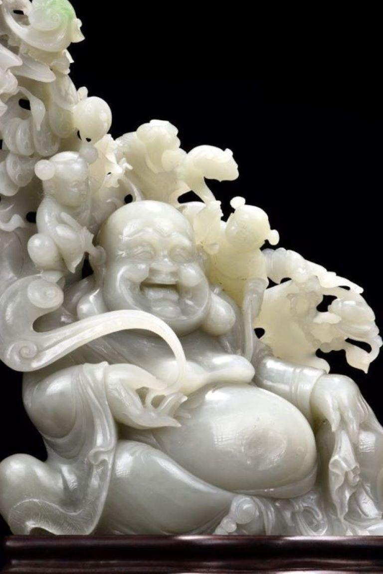 Questa squisita scultura in giada bianca naturale ritrae due giovani fate che interagiscono giocosamente con Milefo, il Buddha che ride. Una fata tiene in mano un Ganoderma Lucidum (Lingzhi), un venerato emblema di longevità e salute, mentre l'altra