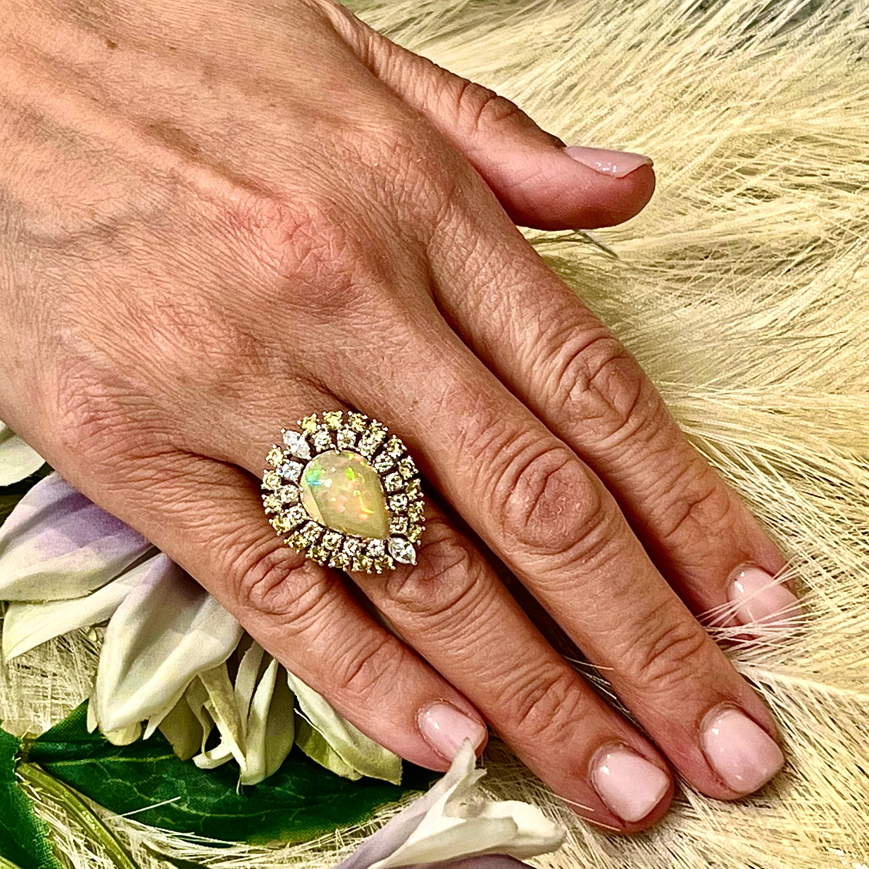 This Magnificent, Custom-Made Natural Fine Quality Pear-Shaped Opal and Diamond Ring is a one-of-a-kind creation that exudes luxury and sophistication. Set in 14k white gold, this stunning piece features a large, fine-quality pear-shaped opal as its