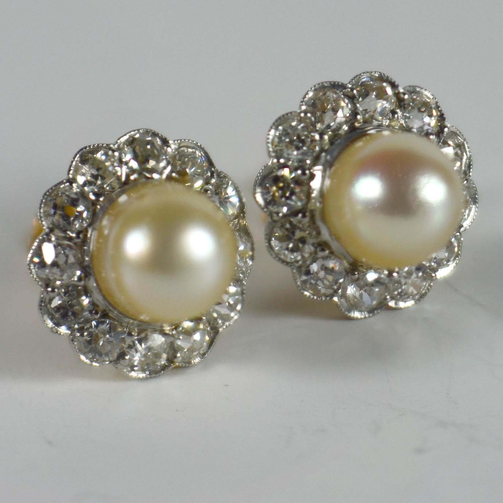 A pair of stud earrings in 18 karat gold and platinum designed as a cluster of white old transition cut diamonds surrounding a natural white pearl. The posts are set with a screw back fitting for added security when wearing these earrings.

Each