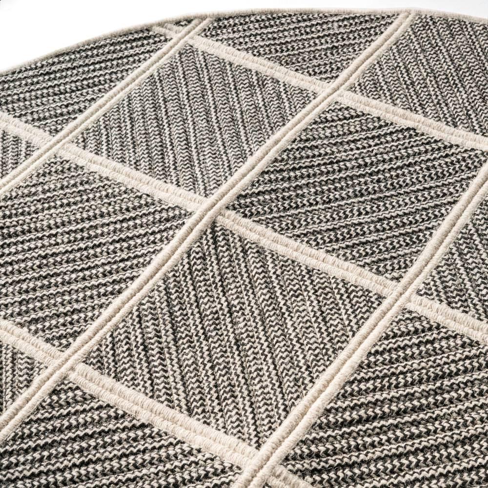 Our Terrain Rug is created by combining black wool blend with a neutral base of light grey natural un-dyed wool. Alternating styles of cable-woven braid is sewn diagonally, combined and then cut into a circle. Designed in the Thayer Design Studio