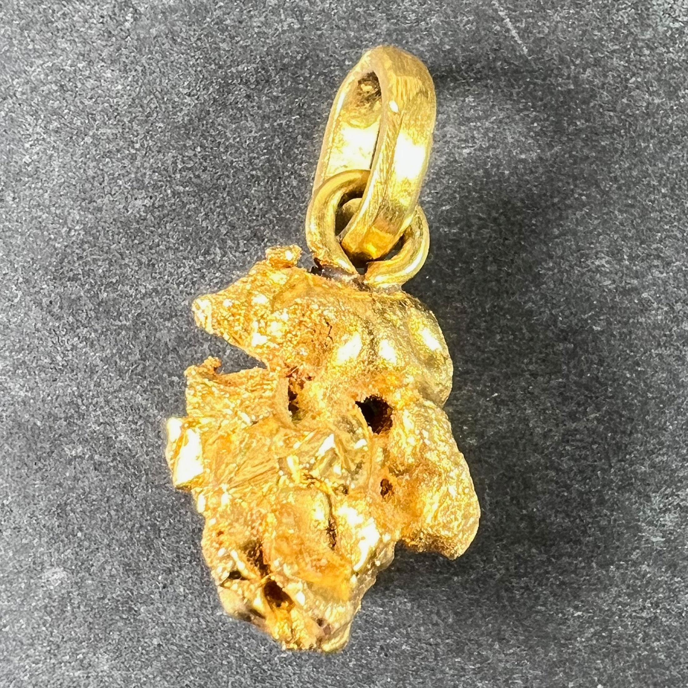 An 18 karat (18K) yellow gold charm pendant designed as a natural, unrefined gold nugget with good cubic crystallisation features including triangular striations. Stamped with the owl head for French import and 18 karat gold. Tests as 18K and