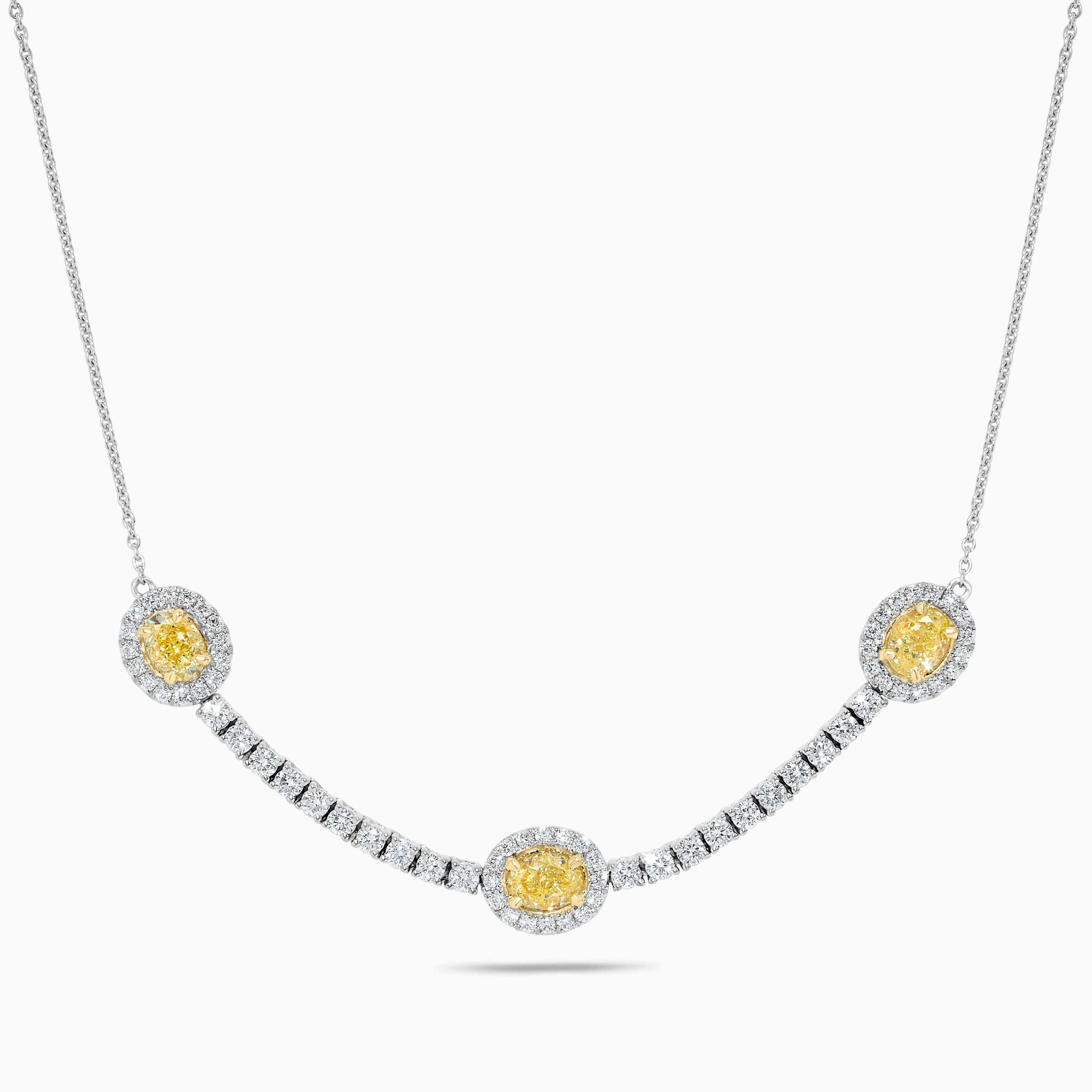 RareGemWorld's classic diamond necklace. Mounted in a beautiful 18K Yellow and White Gold setting with a natural oval cut yellow diamond. The yellow diamond is surrounded by small round natural white diamond melee as well as diamonds throughout the