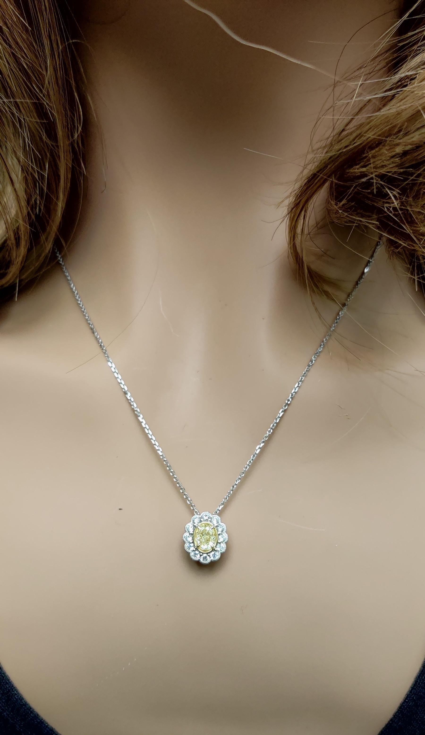 RareGemWorld's classic diamond pendant. Mounted in a beautiful 18K Yellow and White Gold setting with a natural oval cut yellow diamond. The yellow diamond is surrounded by natural round white diamond melee. This pendant is guaranteed to impress and