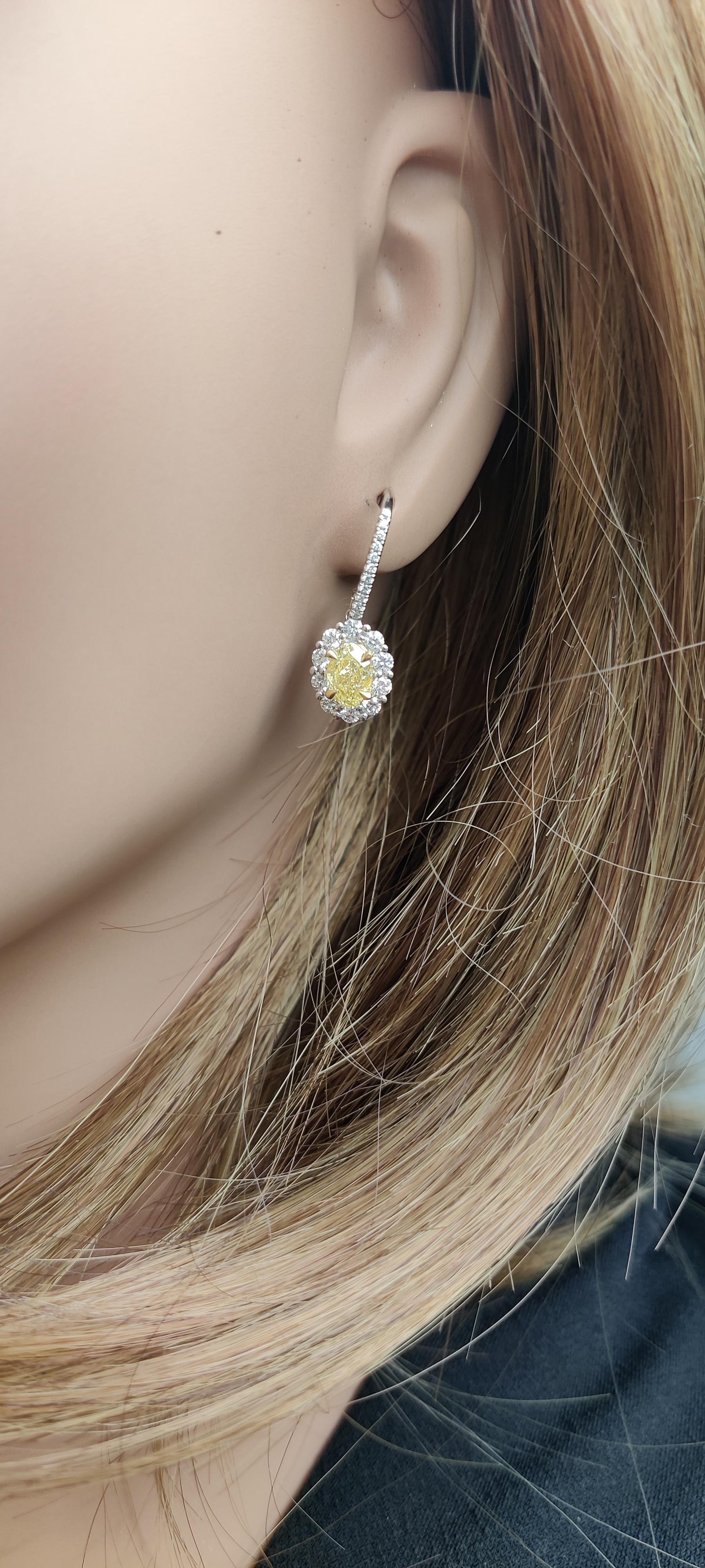 Preciosos pendientes de diamantes de RareGemWorld. Montada en un precioso engaste de oro amarillo y blanco de 18 quilates con diamantes amarillos naturales de talla oval. Los diamantes amarillos están rodeados por un halo de pequeños diamantes