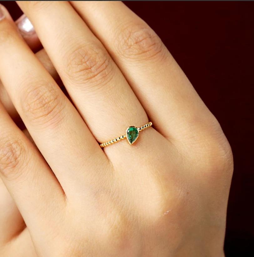 This band ring is made of 14K yellow gold and set with an emerald gemstone. It is the  perfect addition to your fine jewelry collection.

Specifications:

Dimensions: Ring Size-7.25 Us, Top-6*5 MM
Gross Weight: 1.18 gms
Gold Weight: 1.114 gms
Gold