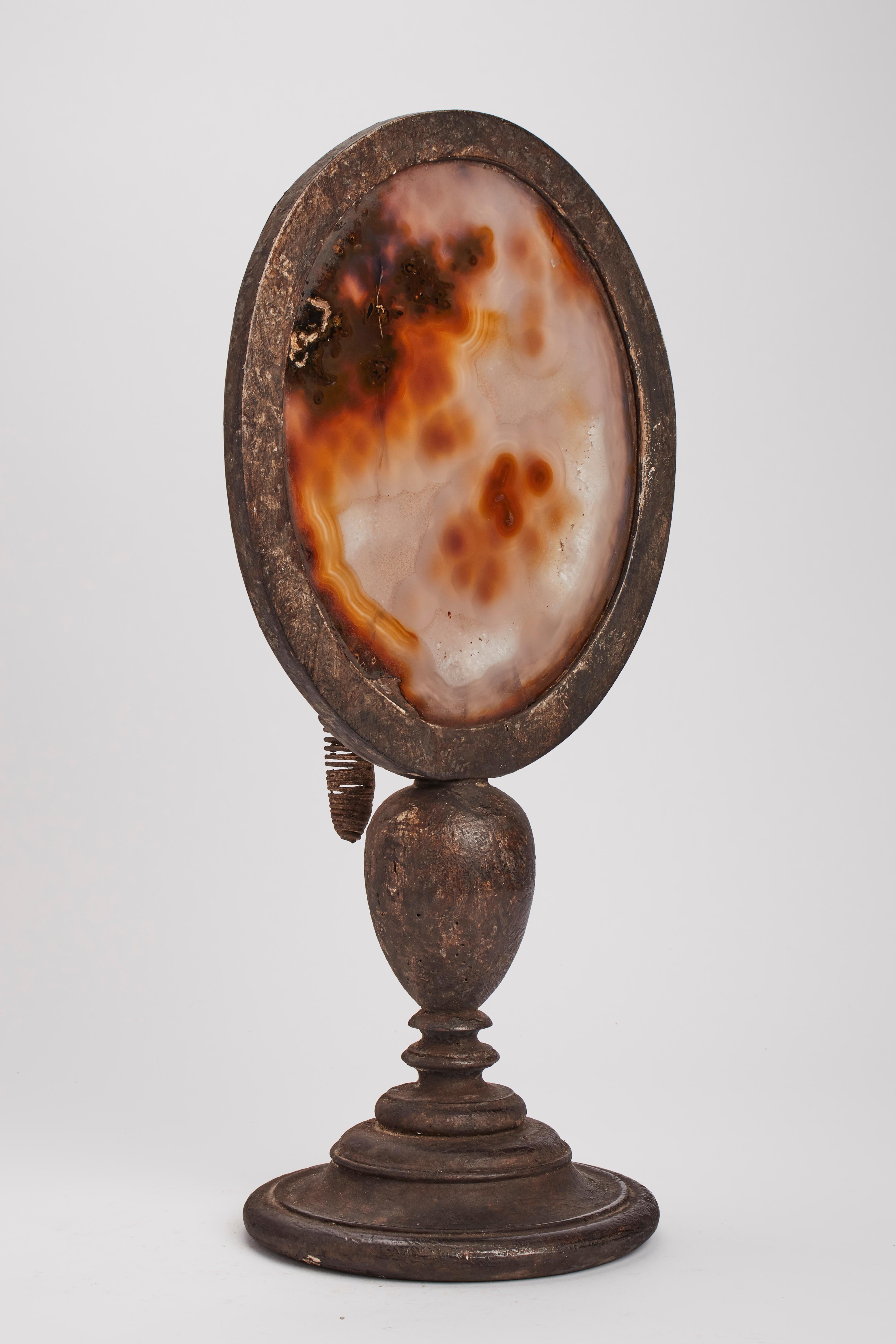 A Wunderkammer naturalia big oval shape agate specimen with a black wooden frame, mounted over a black wooden base, with candle holders. Italy 1880 ca.