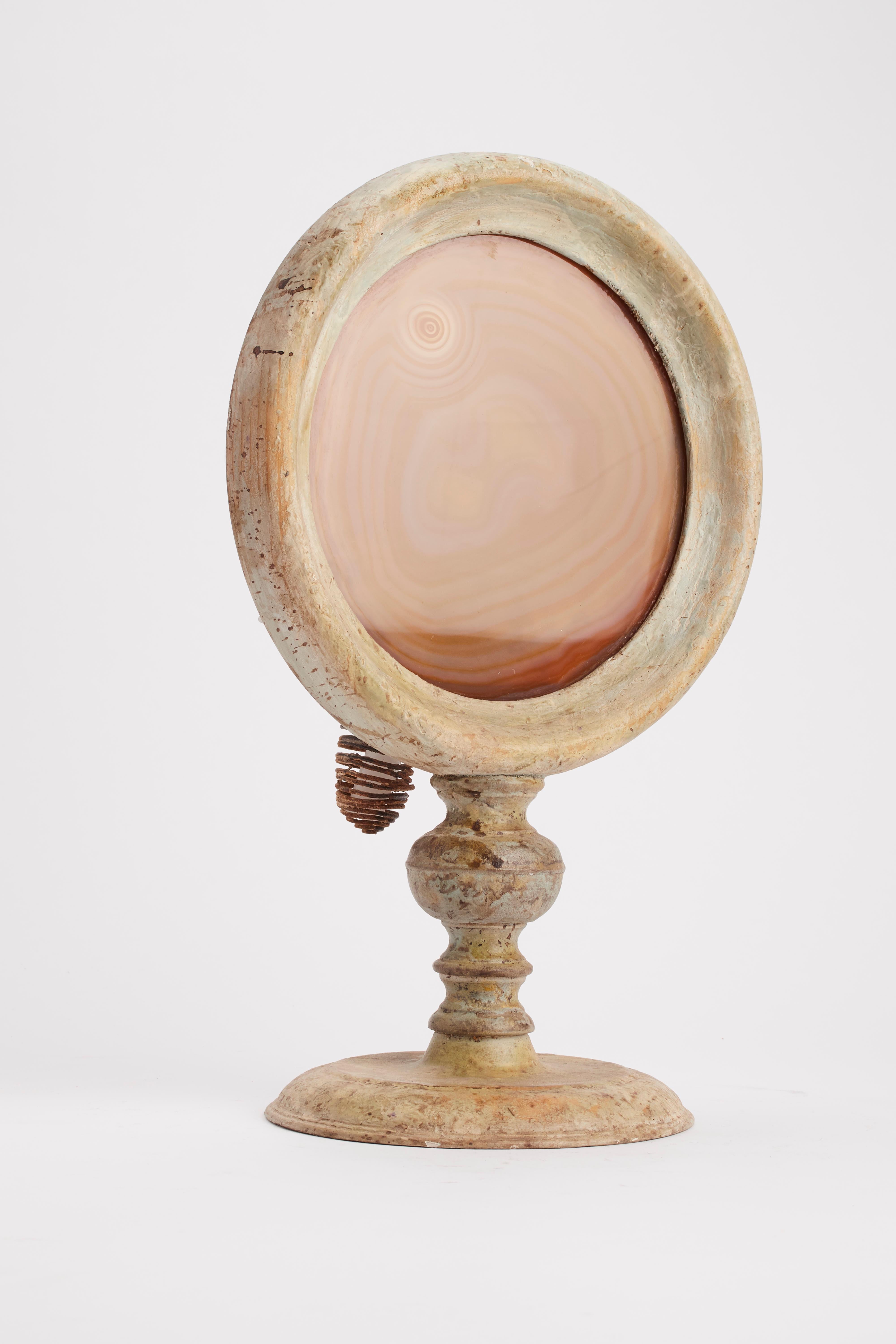 A Wunderkammer naturalia round shape agate specimen with light gray wooden frame, mounted over a light gray wooden base, with candle holder. Italy, 1880 ca.