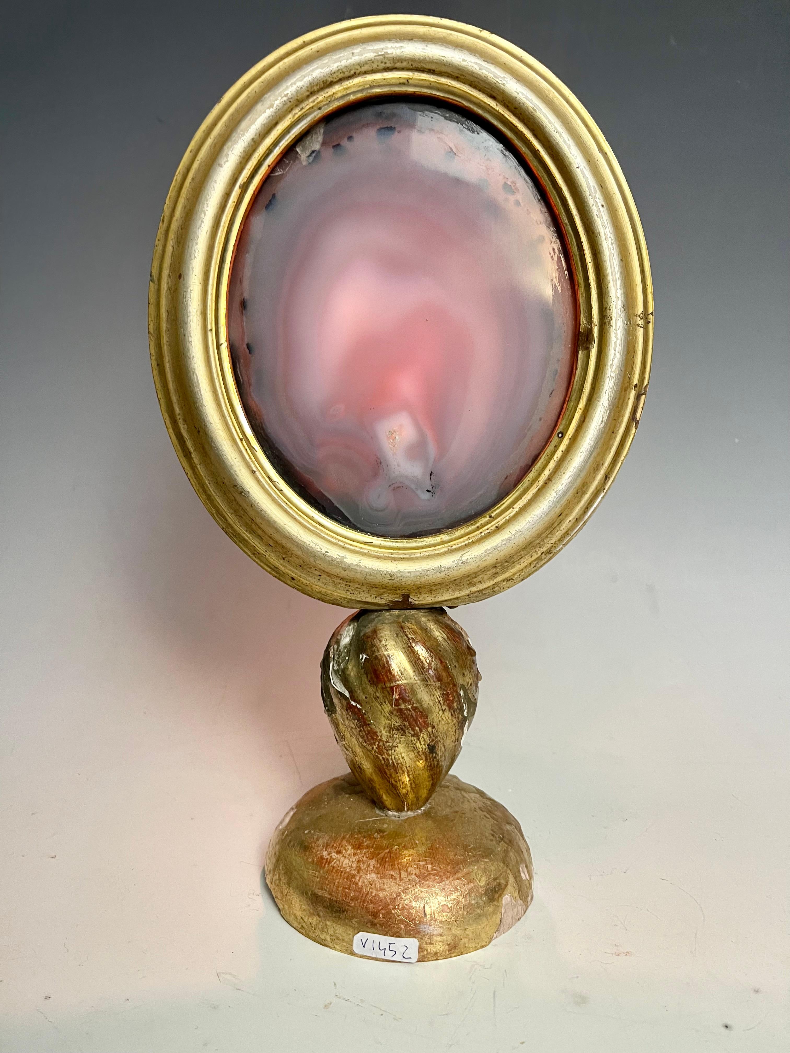 A Wunderkammer natural specimen of an agate, mounted in an oval shape frame over a golden wooden base, with candle holder. Italy, 1880 ca.