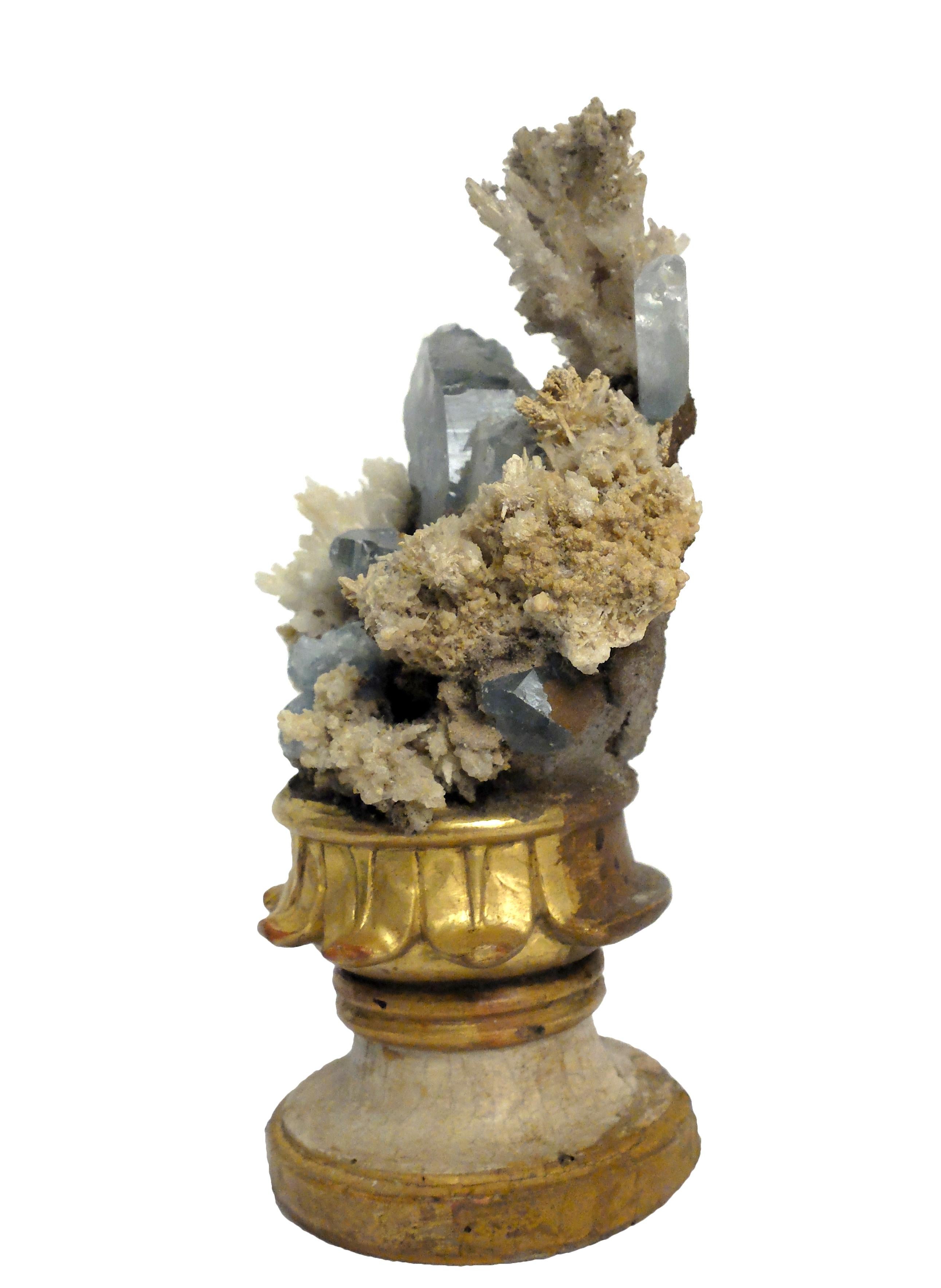 A Naturalia mineral specimen: A composition of Celestite or Celestine and Calcite flowers crystals druze, mounted over guild-plated and lacquered wooden base on a vase shape with leaves decoration.