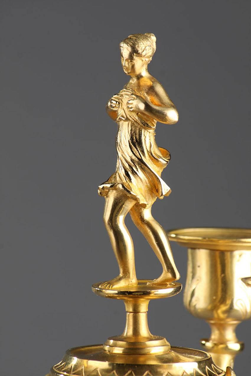 Paar dreiflammige Kandelaber aus vergoldeter Bronze, gekrönt von Dionysos (Bacchus für die Römer) und einer Mänade (Bacchante für die Römer). Dionysos wird mit dem Fell eines Rehkitzes dargestellt, das er in einer Hand hält und in der anderen den