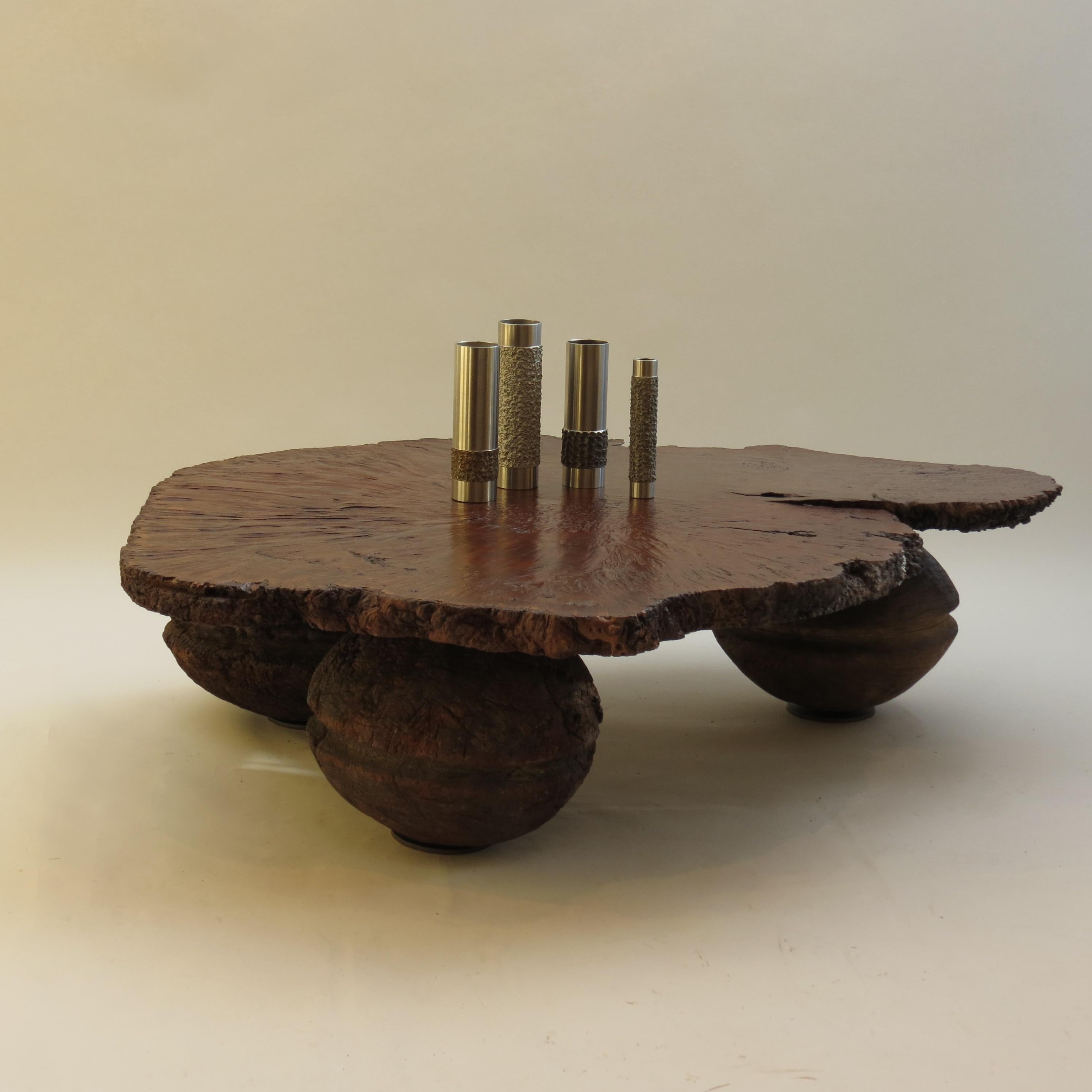 A wonderful bespoke table, made from a very large piece of Australian Karri Wood for the slab top, positioned on three antique Indian rope pulley wheel balls. 

The Karri wood slab has interesting textures and tones; due to shrinkage and Burr wood.