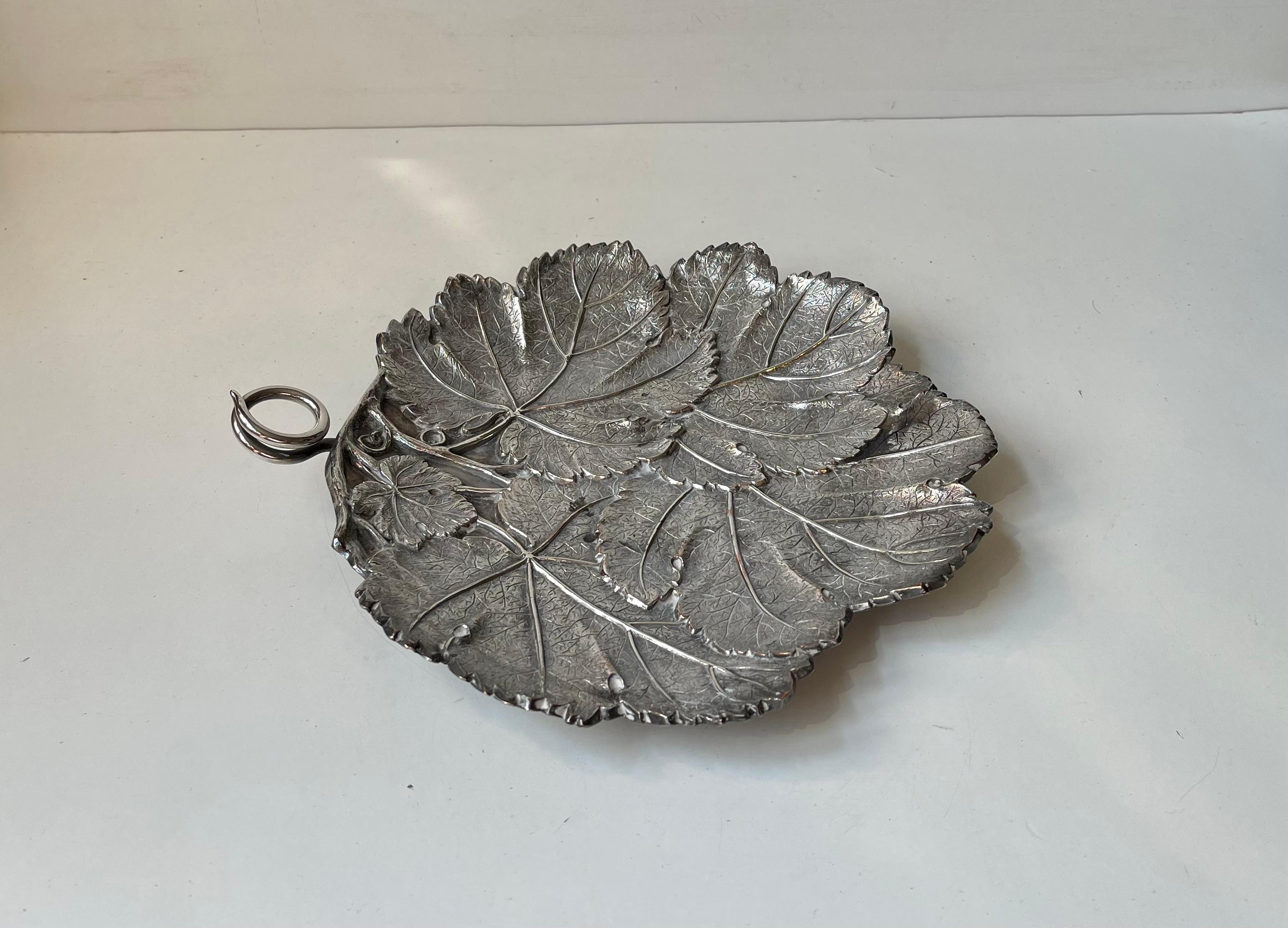 A delicate and naturalistically perceived bowl/dish in sliver plated brass. Entirely micmicing leaves in shape and texture. Small stylized swirling handle. Designed and made at Berg Denmark circa 1950-60 in a style reminiscent of Buccellati.