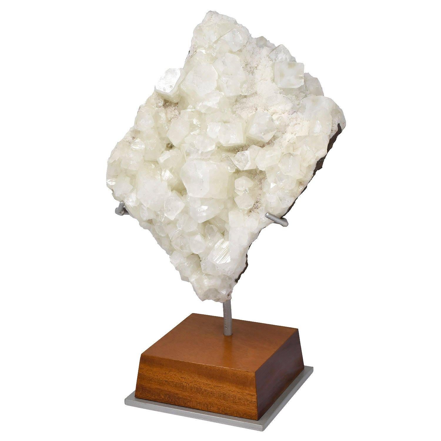 Naturally formed mineral, clear apophyllite sculpture

India

Measures: 11 x 8 x 4 in. / 28 x 20 x 10 cm

Height on custom display stand: 14 in. / 36 cm

Custom mounted on a nickel-painted steel and bevelled cherry wood base.

