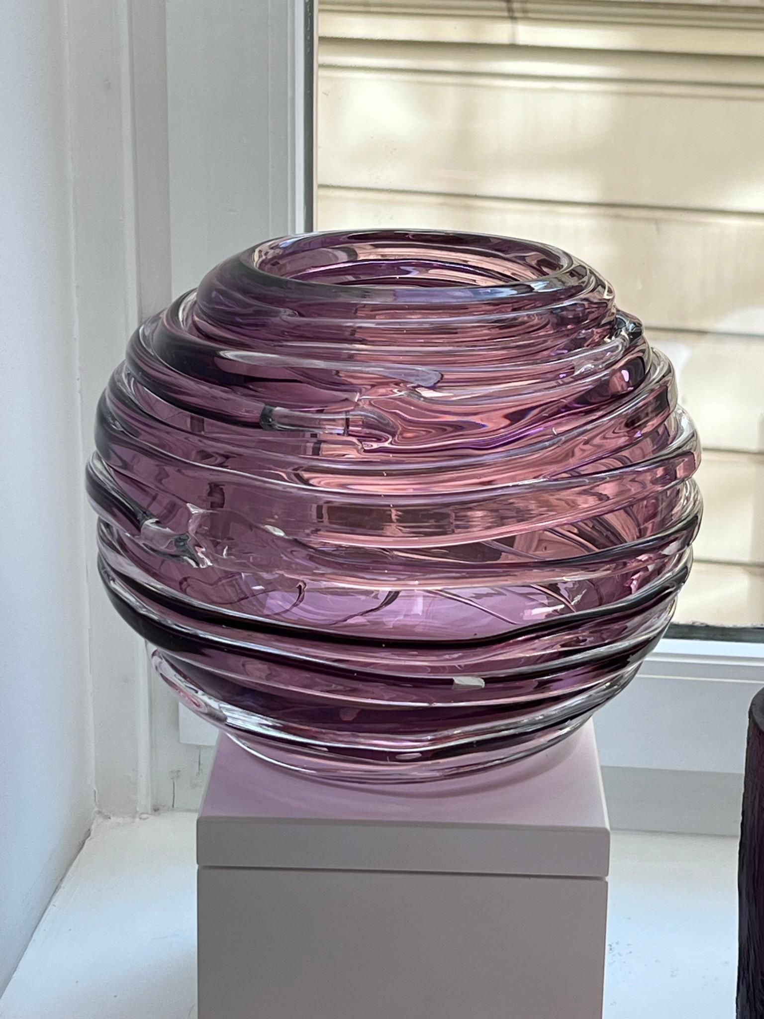 This mouth-blown glass vase is completely hand-crafted in a beautiful amethyst color with clear ribbed details. Measuring 21 cm (8.25 inches) in diameter, it is the perfect size for everyday flowers and looks equally stunning as a stand alone