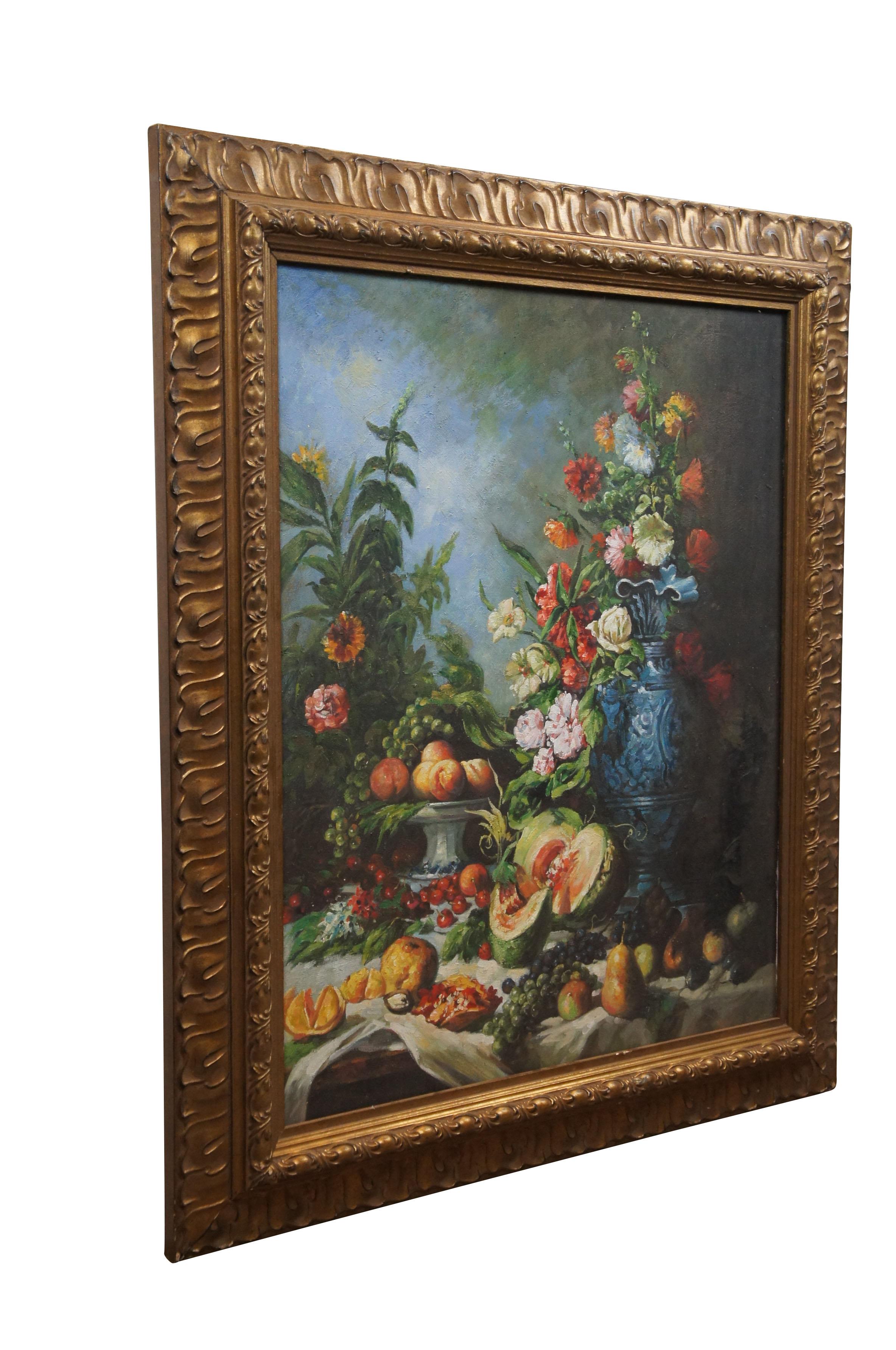 Vintage 20th century oil painting on canvas after a still life attributed to Eugene Vidal, depicting a bouquet of flowers in a large blue vase, surrounded on a cloth covered table with an array of fruits. Carved gold frame, made in Italy.

