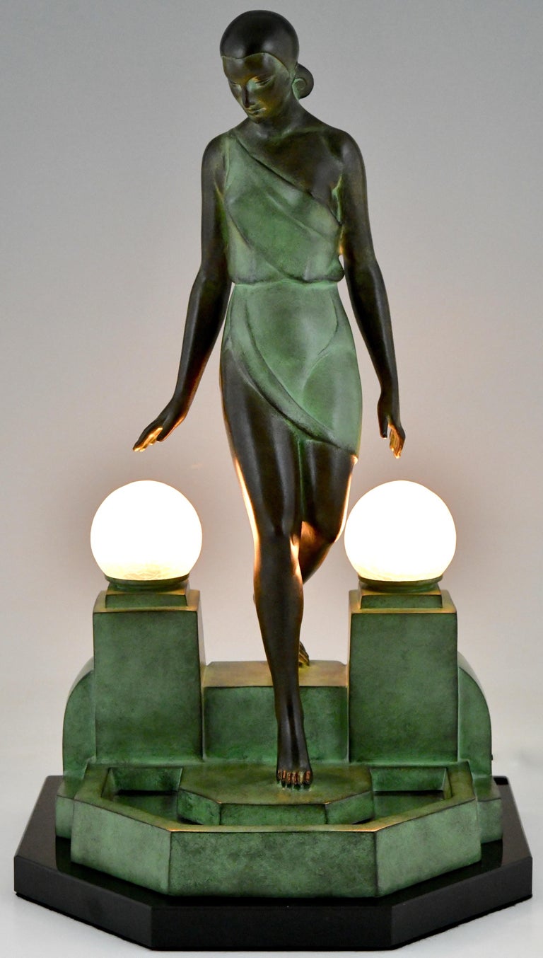 Nausicaa, Art Deco style lamp lady at a fountain.
Signed Fayral, pseudonym of Pierre Le Faguays.
Foundry mark Max Le Verrier foundry. 
Design 1930.
Posthumous contemporary cast at the Le Verrier foundry. 
Art metal, patinated. Frosted crackle glass
