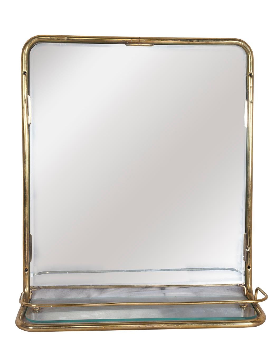 A great brass wall mirror from the stateroom of a decommissioned European cruise ship. It features a new mirror and glass shelf with the original brass railing around it, circa 1960s. When found, these had been slathered with white paint and all the