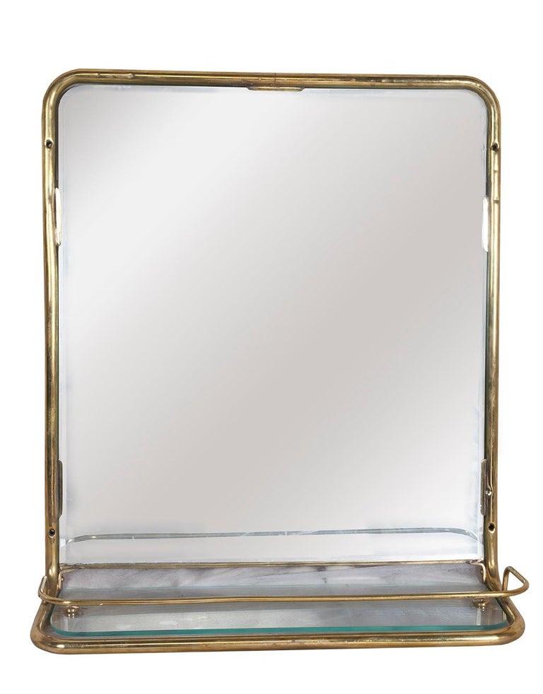 Un superbe miroir mural en laiton provenant de la cabine d'un bateau de croisière européen désaffecté. Elle comporte un nouveau miroir et une étagère en verre, entourés de la rambarde en laiton d'origine, vers les années 1960. Lorsqu'ils ont été