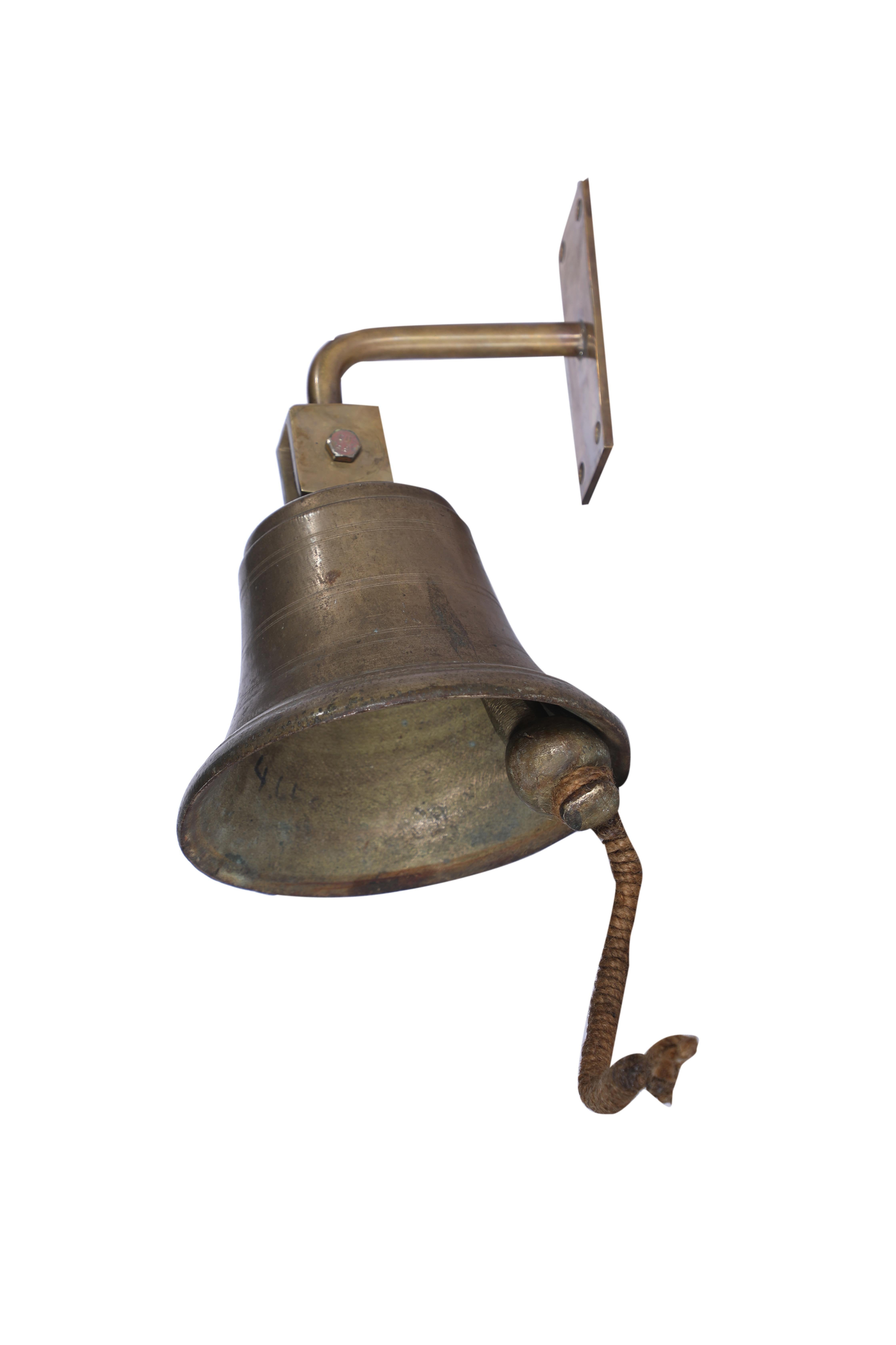 A brass bell used on a ship which was decommissioned.  It has a coiled rope pull attached to the clapper.  The brass bracket and base plate has been added  for ease of hanging and measures 2 inches x 6 inches.  Circa 1970's.  Also has a nice ring.