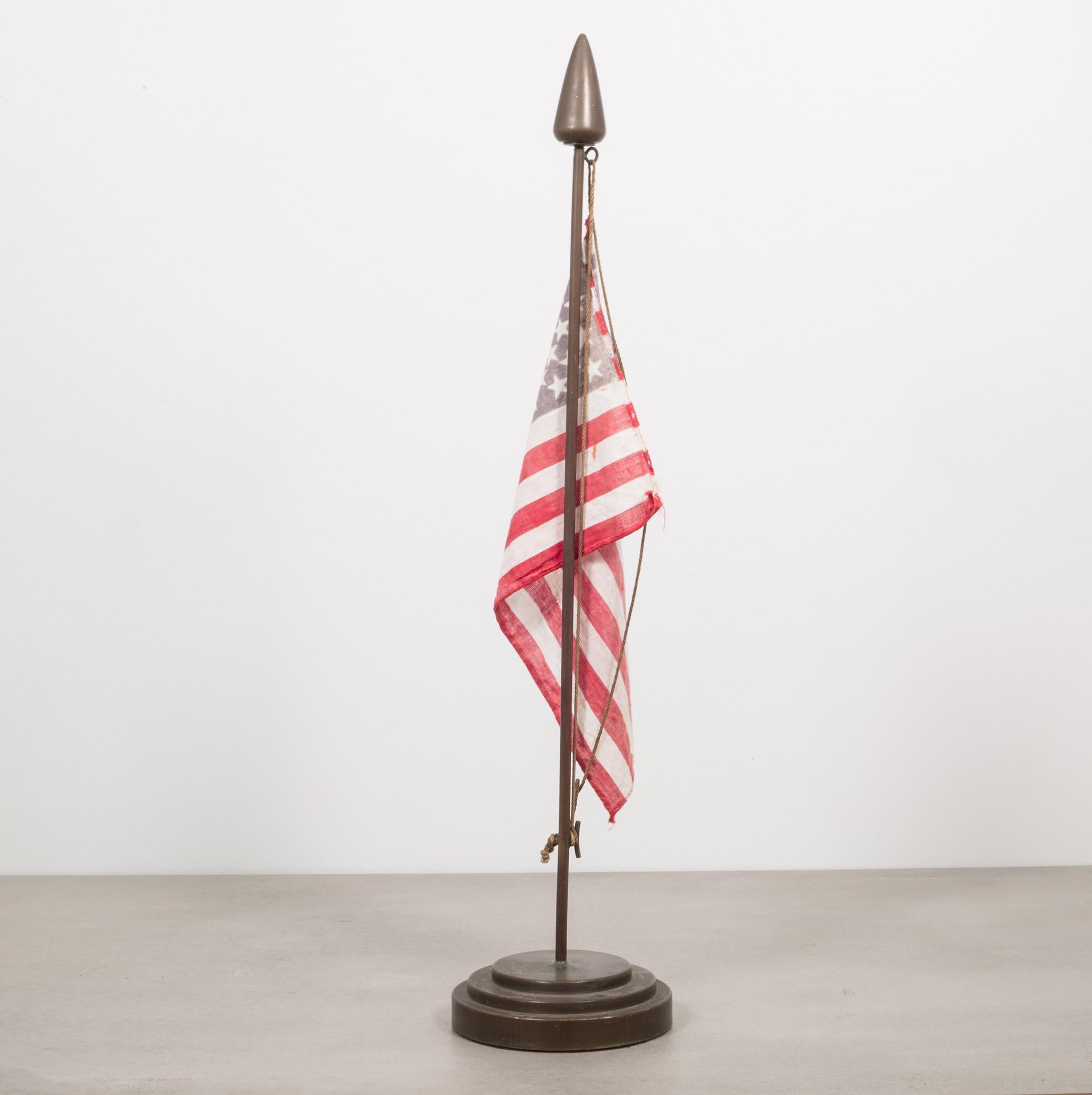About

This is an original heavy bronze flag stand with an American flag. This piece was designed for a large boat or military ship to stay stationary on a desk while at sea. The bronze stand has a round, graduated step base with green velvet. The