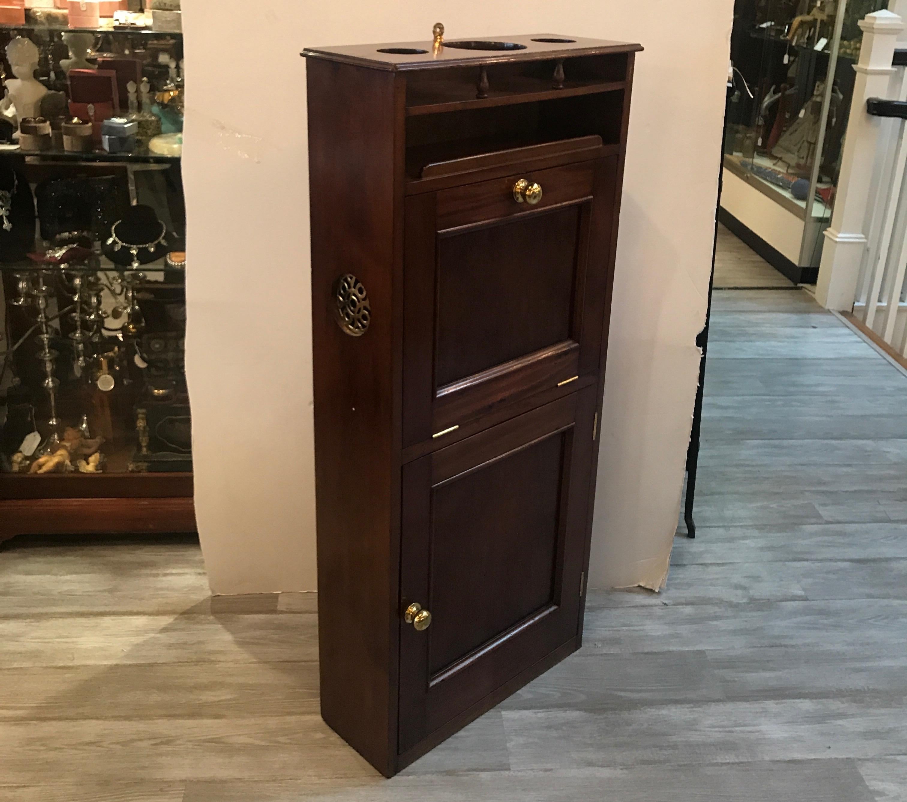 A remarkable mahogany cabinet with a concealed sink. The cabinet was from a 1920s yacht with has a fall front door that reveals a fold out nickel-plated wash basin with a lowed copper pot for used water storage.